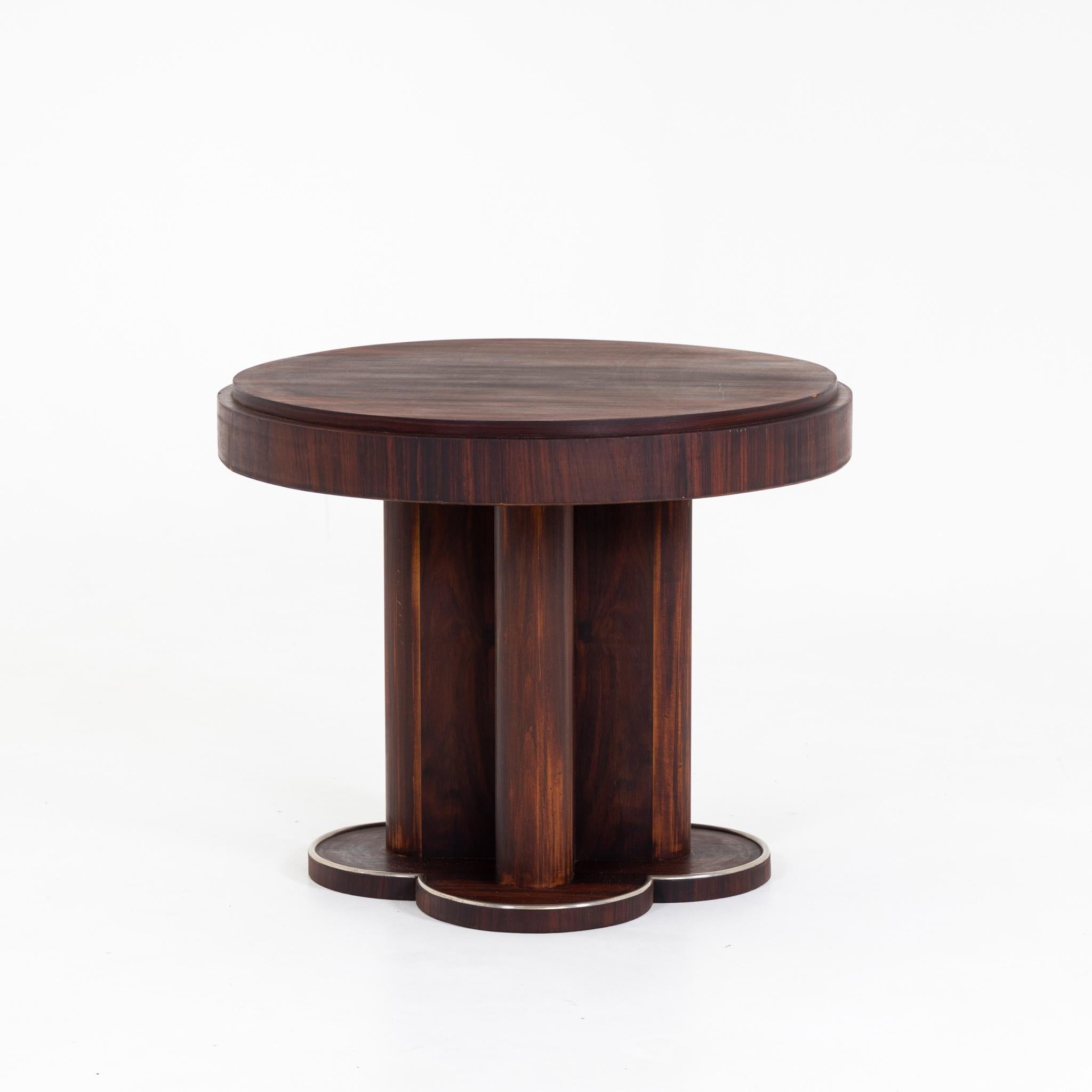 Table standing on four-piece pedestal with round tabletop and cross-shaped pedestal column.