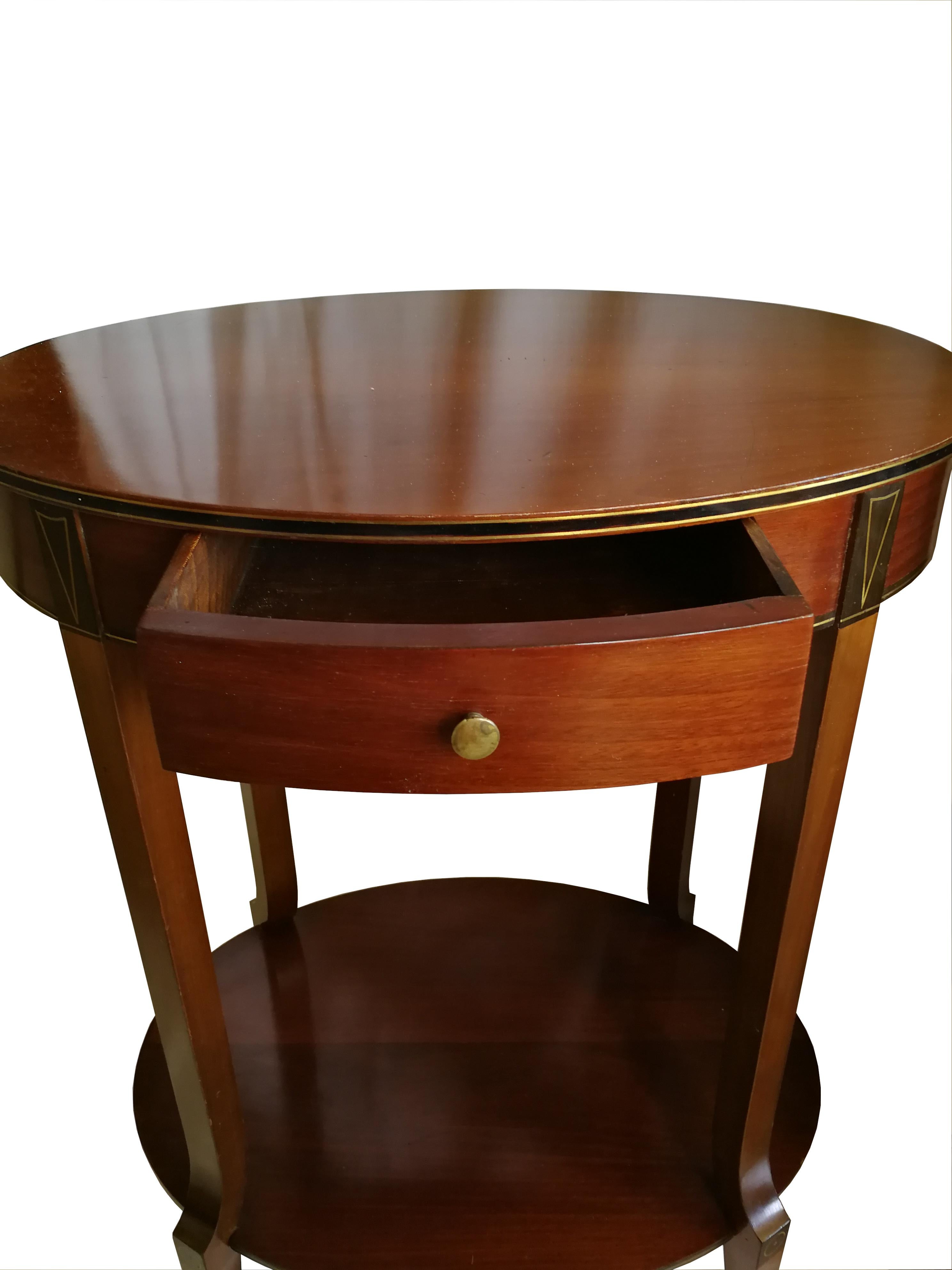 Very elegant small oval Art Deco side table or nightstand in mahogany with 2 levels, a drawer and styled bronze inlays. 
 France circa 1920.

 