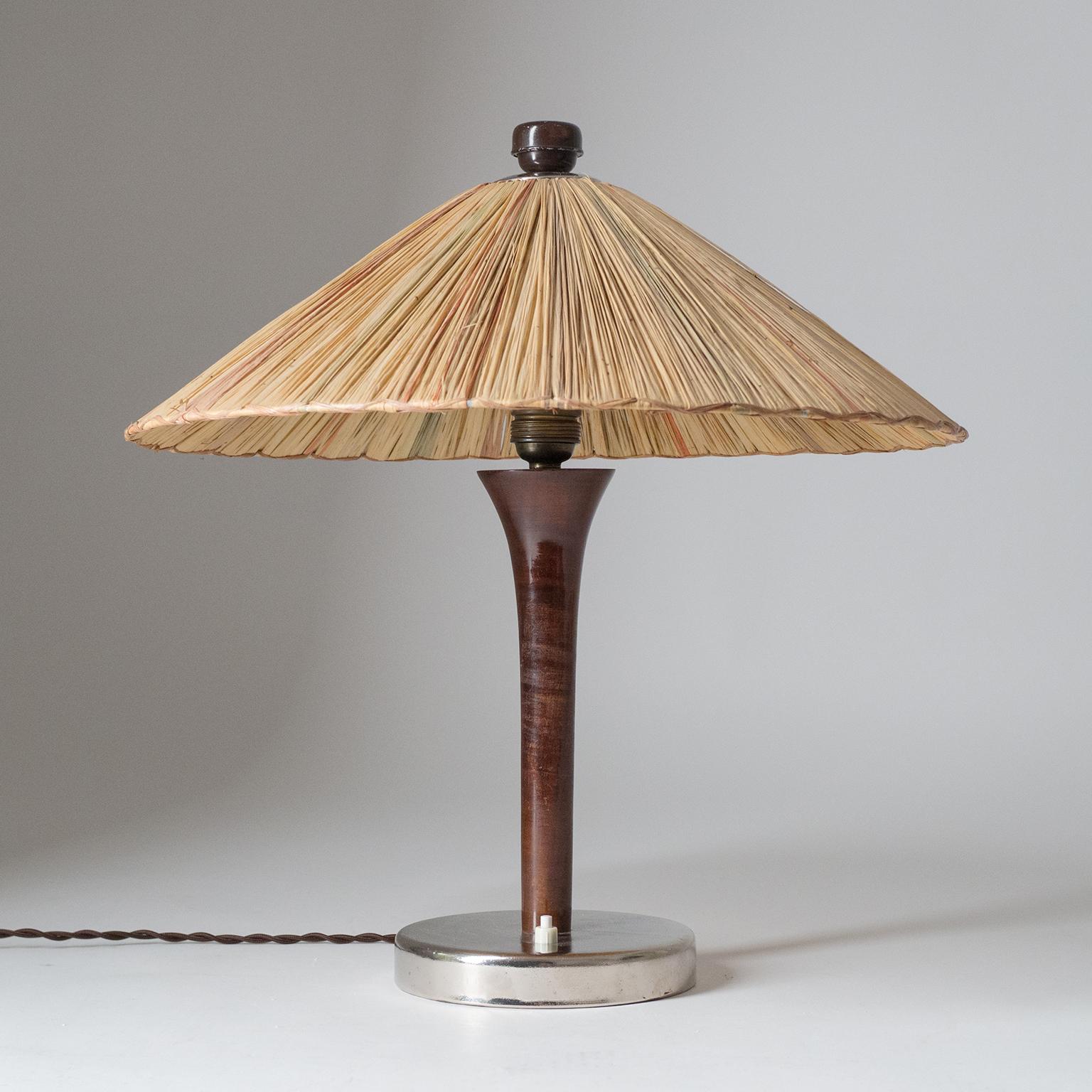 Rare 1930s table lamp with original straw shade. A weighted and chromed base holds a turned Tulip-shaped wooden stem and a large straw shade with different colored elements. Nice original condition with minor patinato the chrome and lacquered