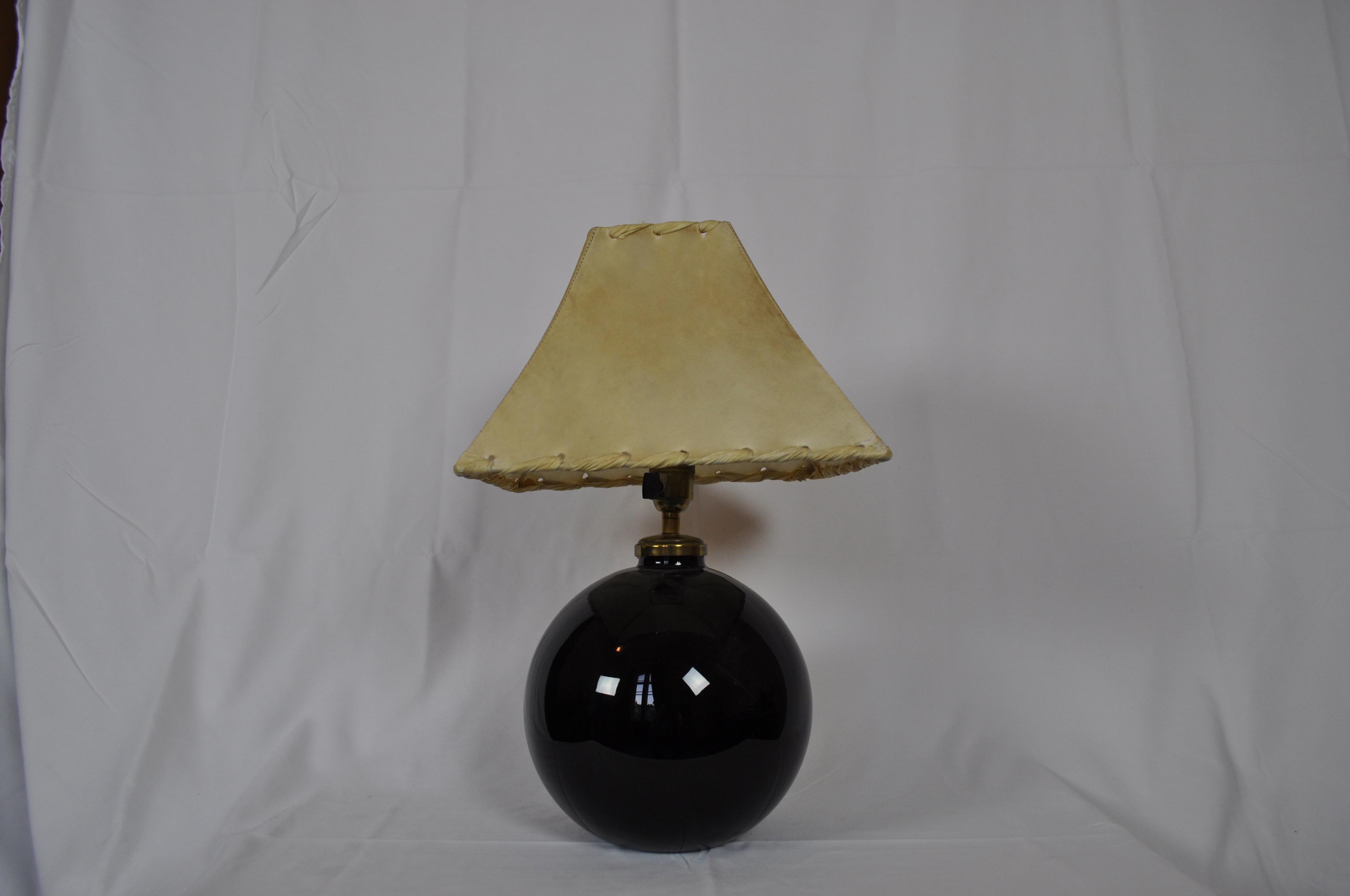 Art Deco table lamp designed and produced by Jacques Adnet in the 1940s. The lamp is made in black opaline, details in brass and parchemunt top. The lamp comes with authentication document.