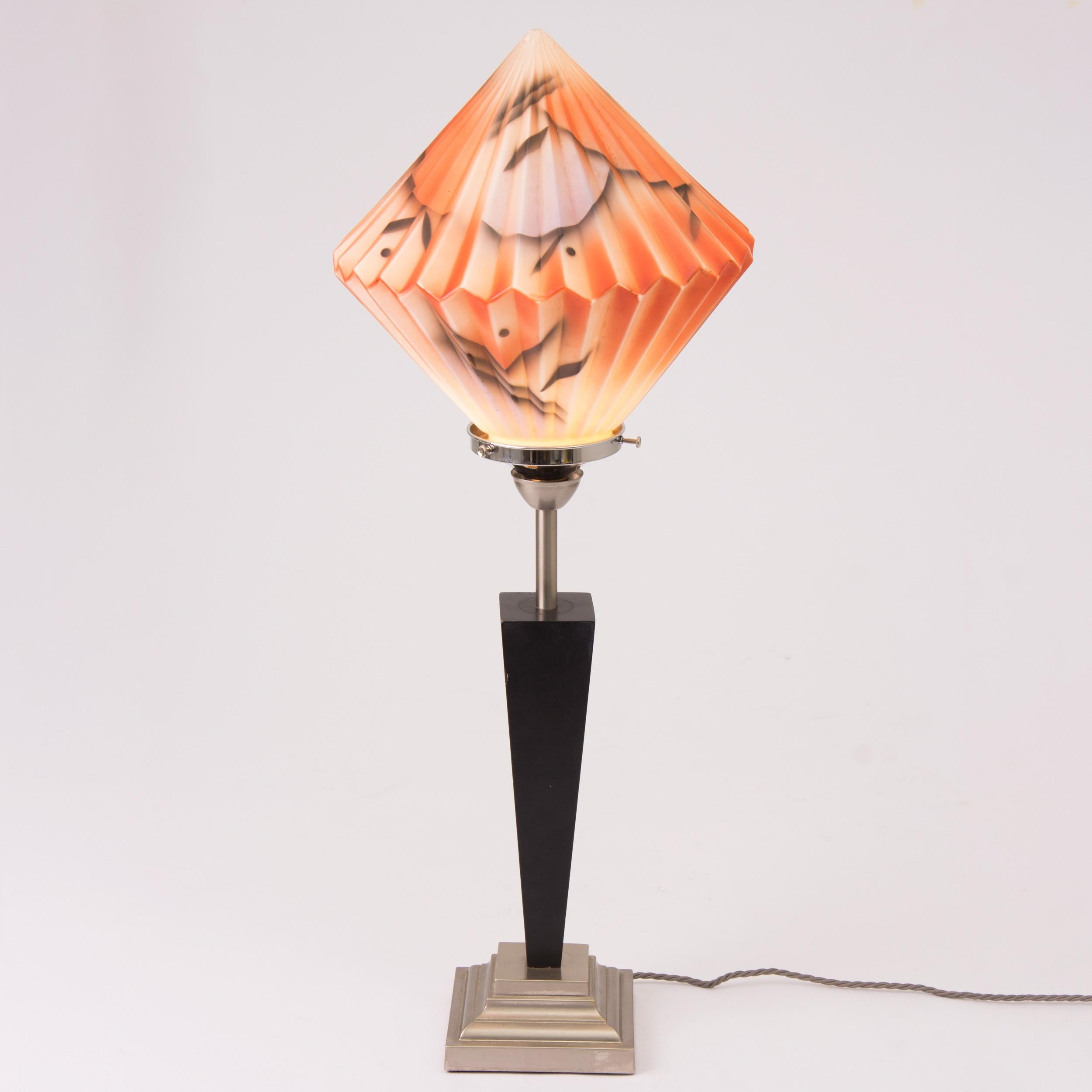 Large Art Deco table lamp with a pleated diamond shape glass shade with a painted abstract design, on a tall tapered column.
British, circa 1930.
Measures: H 79cm, W 31cm, D 31cm.