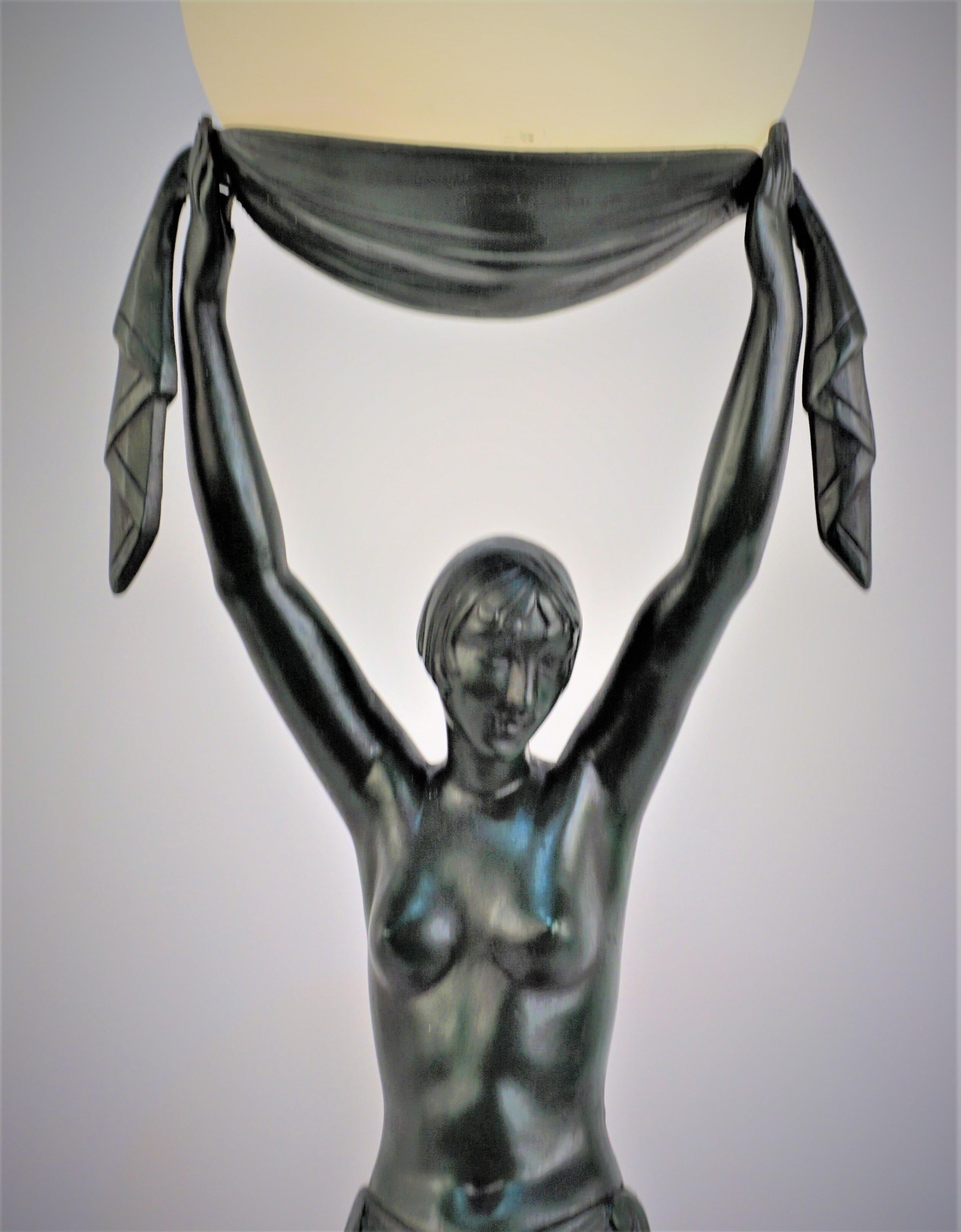Beautiful Art Deco dark green with black patinated metal sculptural table lamp by Pierre Le Faguays, France c. 1930. It depicts a female standing on a marble base holding glob glass shade above her head.
*Signed 
