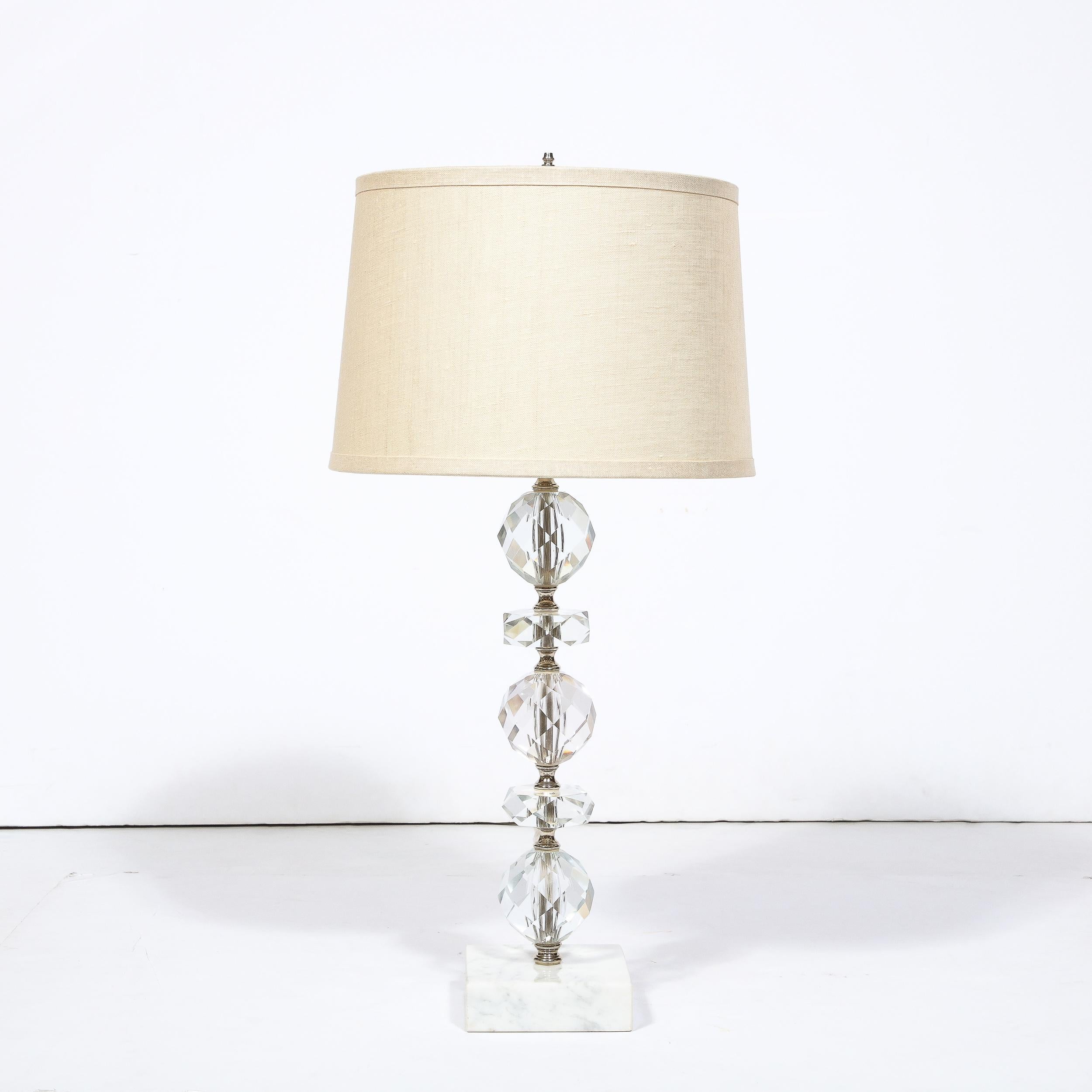 This lovely Art Deco Table Lamp in Faceted Cut Crystal and Marble Base originates from the United States, Circa 1945. Featuring a body composed of Cut Crystal in alternating spherical and flattened elements rising from a rectilinear base of Carrara