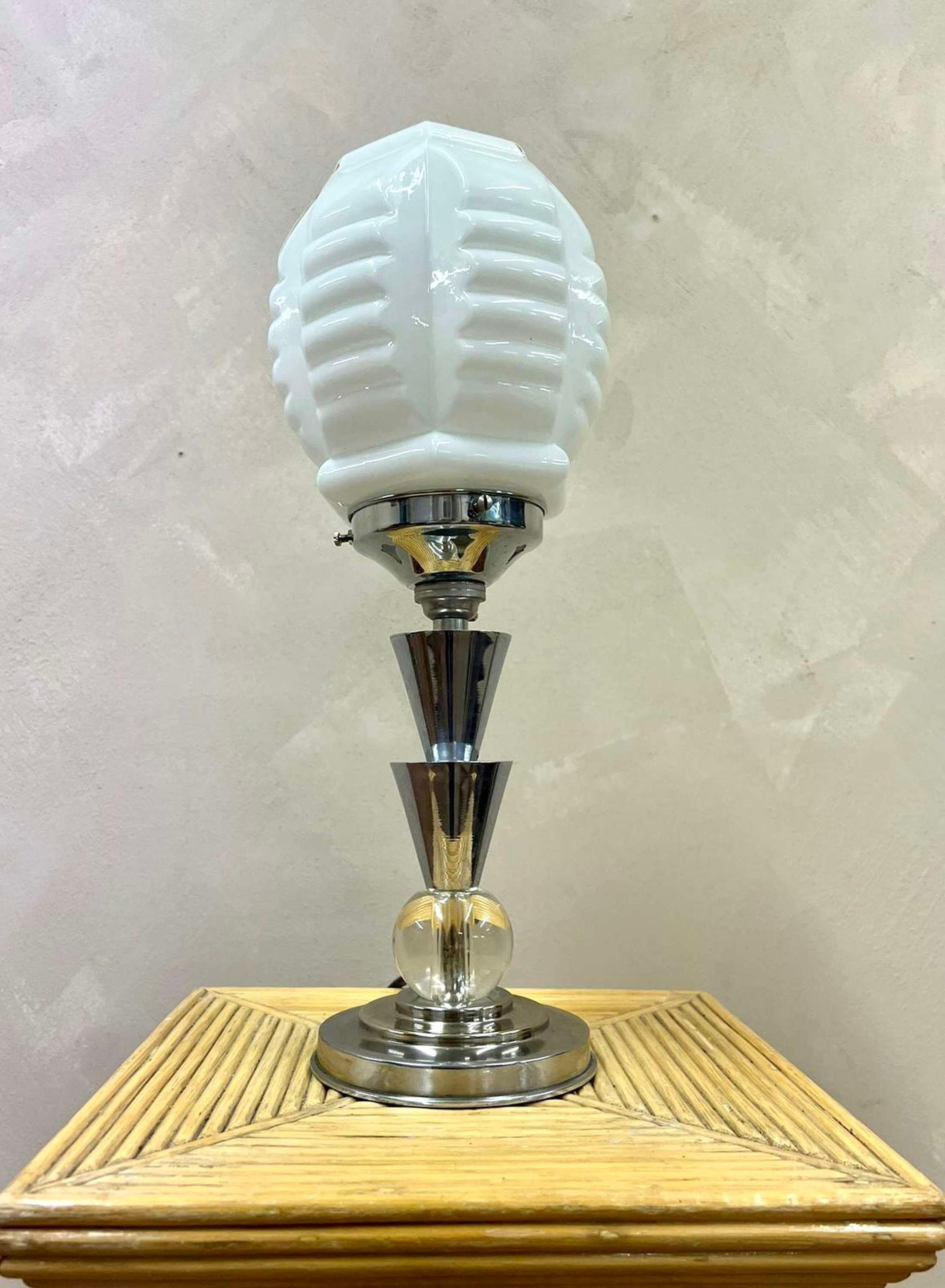 A rare Art Deco table lamp, in the manner of designer Jacques Adnet (1900-1984)
An unusual shape opaline glass shade sits above a stem comprising of chromed cones over a glass ball and tiered base of 12cm diameter.

Wired and pat tested 
If
