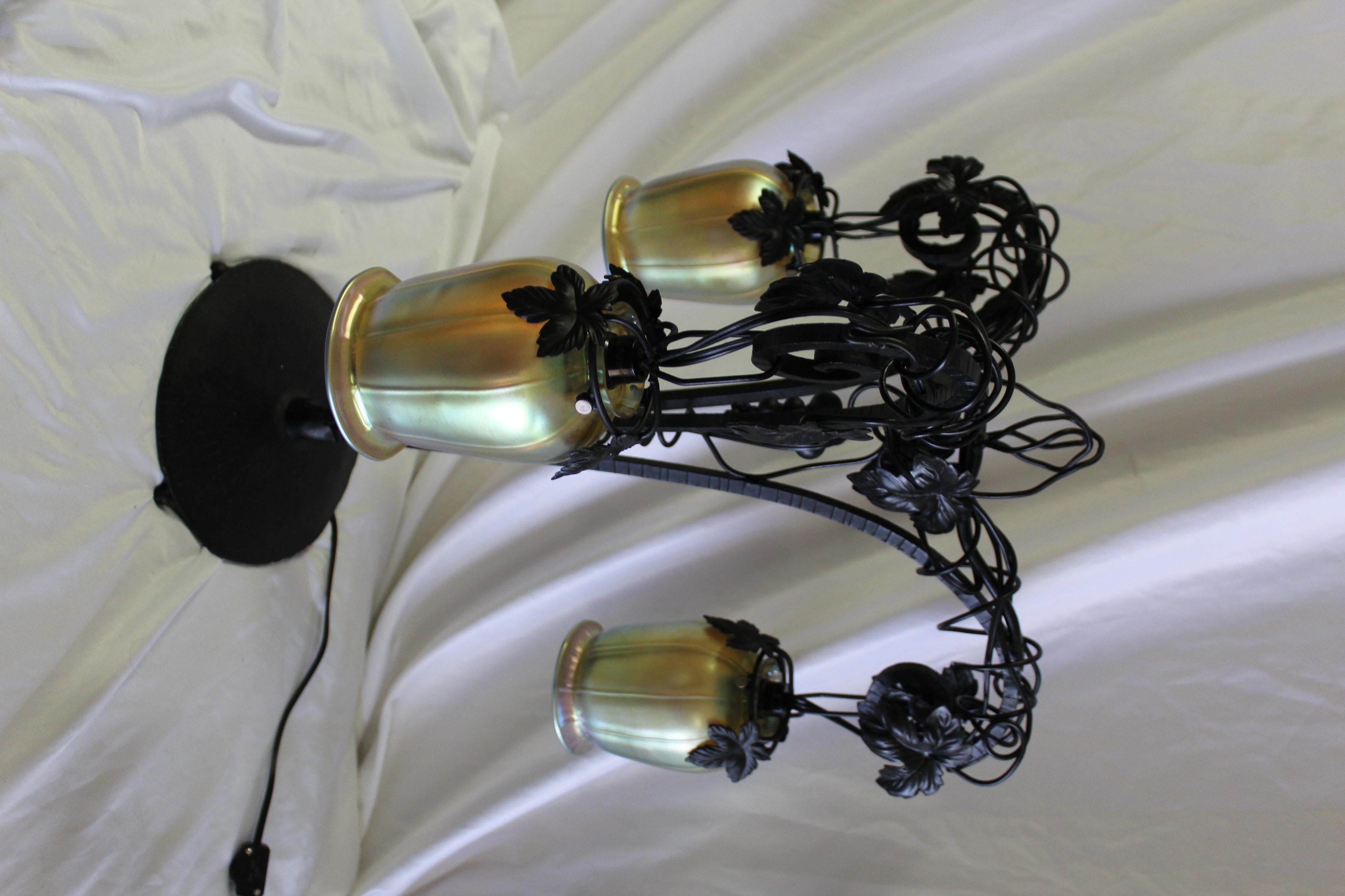 Handgeschmiedete Eisenlampe mit Weinrebe. Schwarzes Seidenmatt-Finish mit 3 goldenen Favril-Glasschirmen. Entworfen nach E. Brandt. Sieht toll aus, wenn es beleuchtet ist.