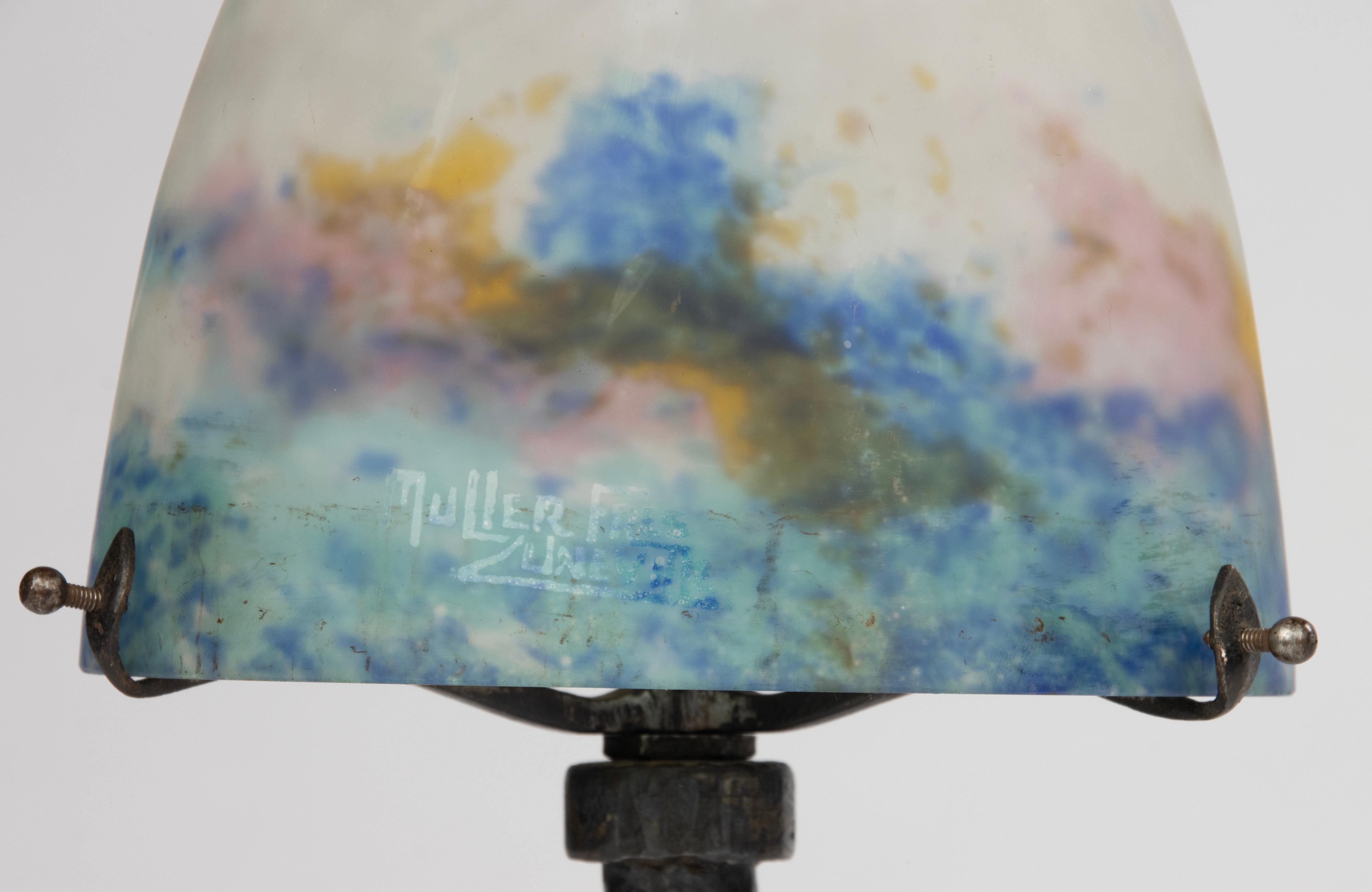A beautiful Art Deco table lamp, made by the famous French maker Muller Frères.
The base is made of wrought iron. The shade is made of paste glass (pate-de-verre), the outside of the shade is satined.
The glass has a subtle color gradient, which