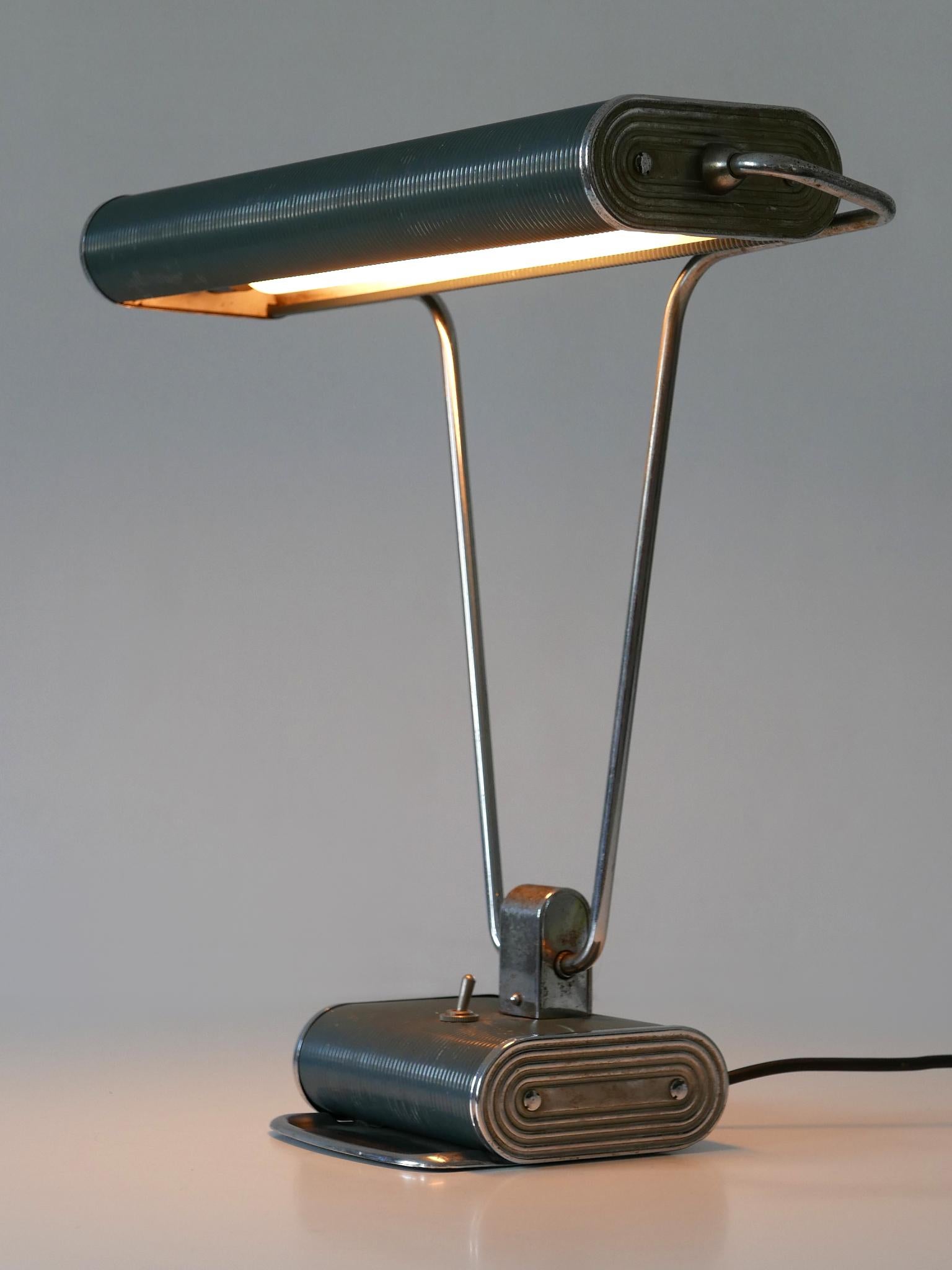 Elegante lampe de table ou de bureau Art Deco 'No 71' de couleur bleu-gris et argent. Abat-jour rotatif. Conçu par André Mounique pour Jumo, France, années 1930.

Un total de 5 lampes en deux couleurs est disponible !
Il s'agit du numéro 4 des cinq