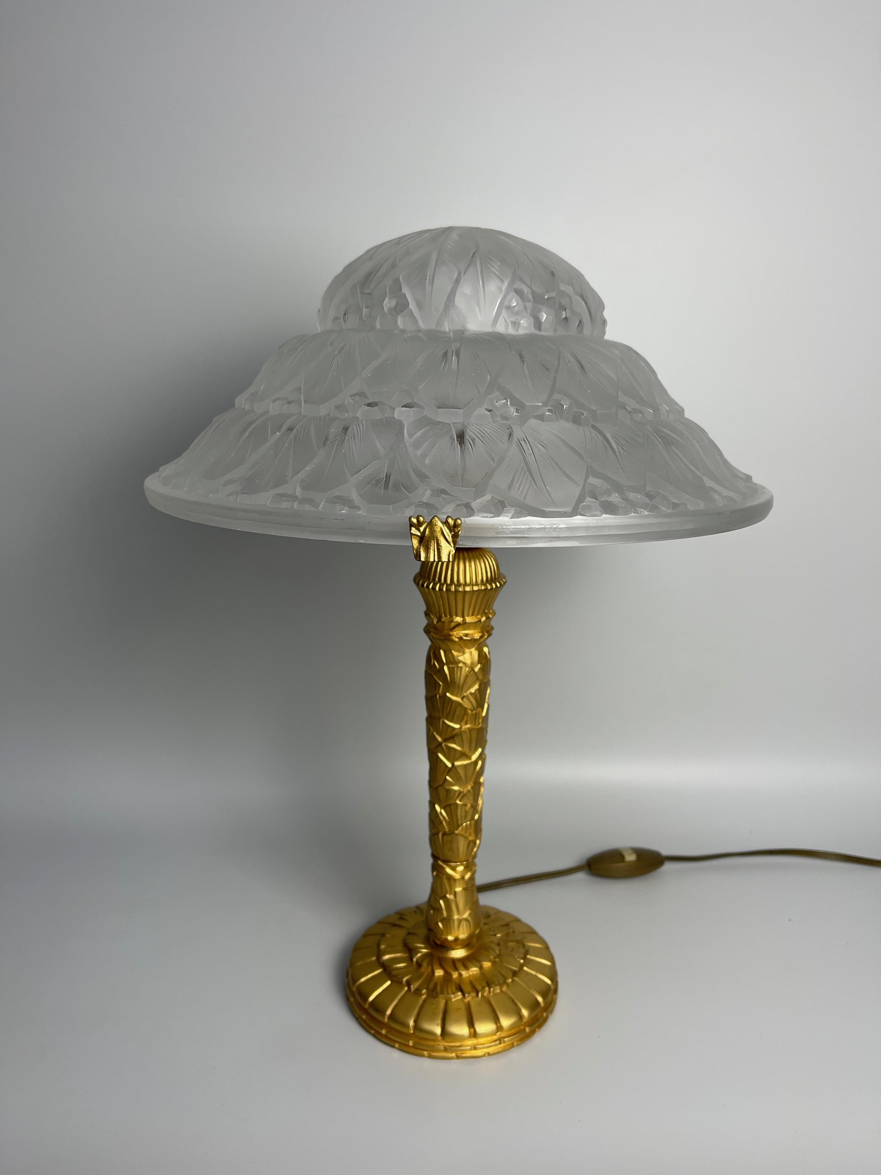 Art deco lamp around 1930.
Gilt bronze foot decorated with banana leaves. Very good quality of carving
Note however some wear on the gilding, clearly visible in the photos.
Lamp cap in pressed molded glass also decorated with banana leaves.