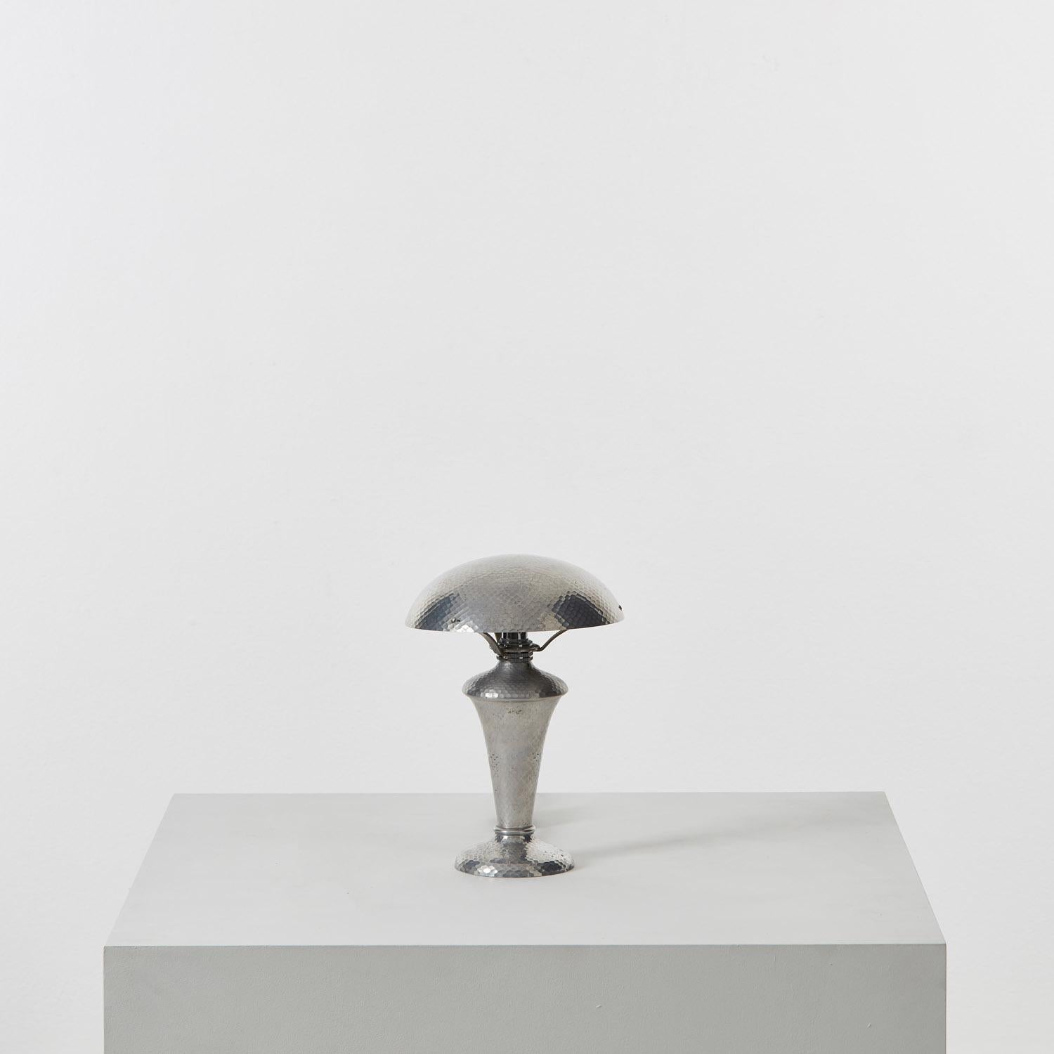 With an urn-like base and saucer shade, this hammered metal table lamp points to the pursuit of balance in Art Deco design. The textured effect was not widely used at the time, and absent from better-known Bauhaus silhouettes.