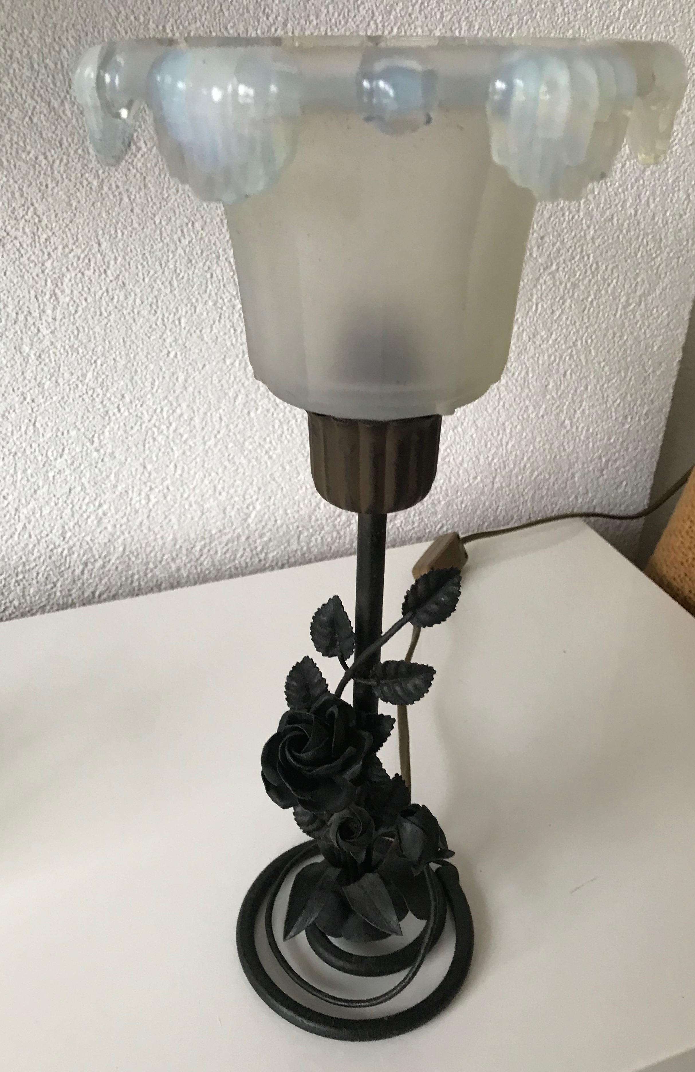 Rare 1920s wrought iron table lamp with a René Lalique style shade.

With perfectly hand forged branches, leaves and roses at the base of this finest workmanship table lamp, it is as sturdy and stable as the day it was made. The stunning glass shade