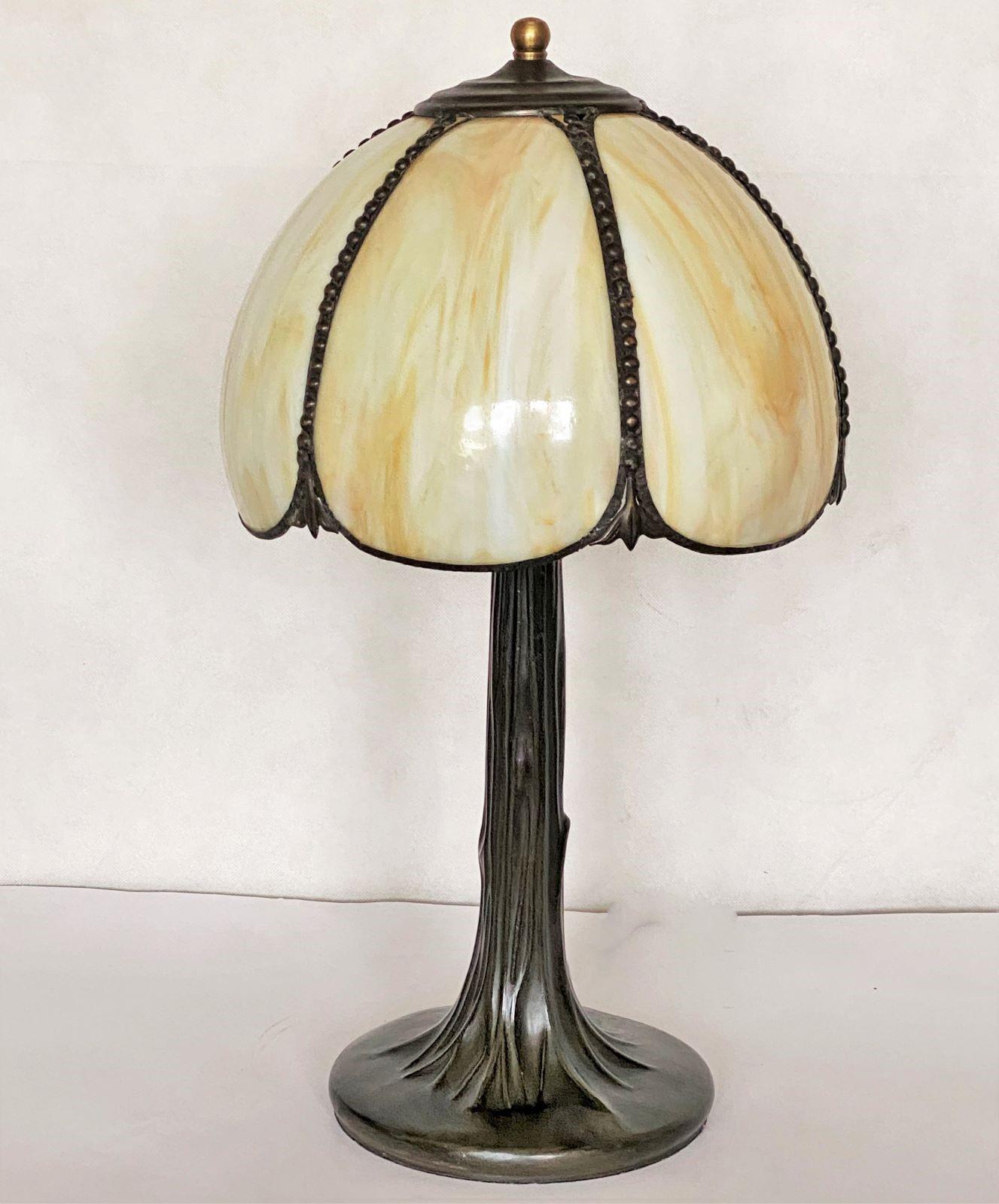A French Art Deco table lamp from 1930-1939. Dome form shade with six bent slag glass panels beautifuly connected with brass on a patinated brass tree trunk shaped base. The table lamp is in very good condition and has been recently rewired. It