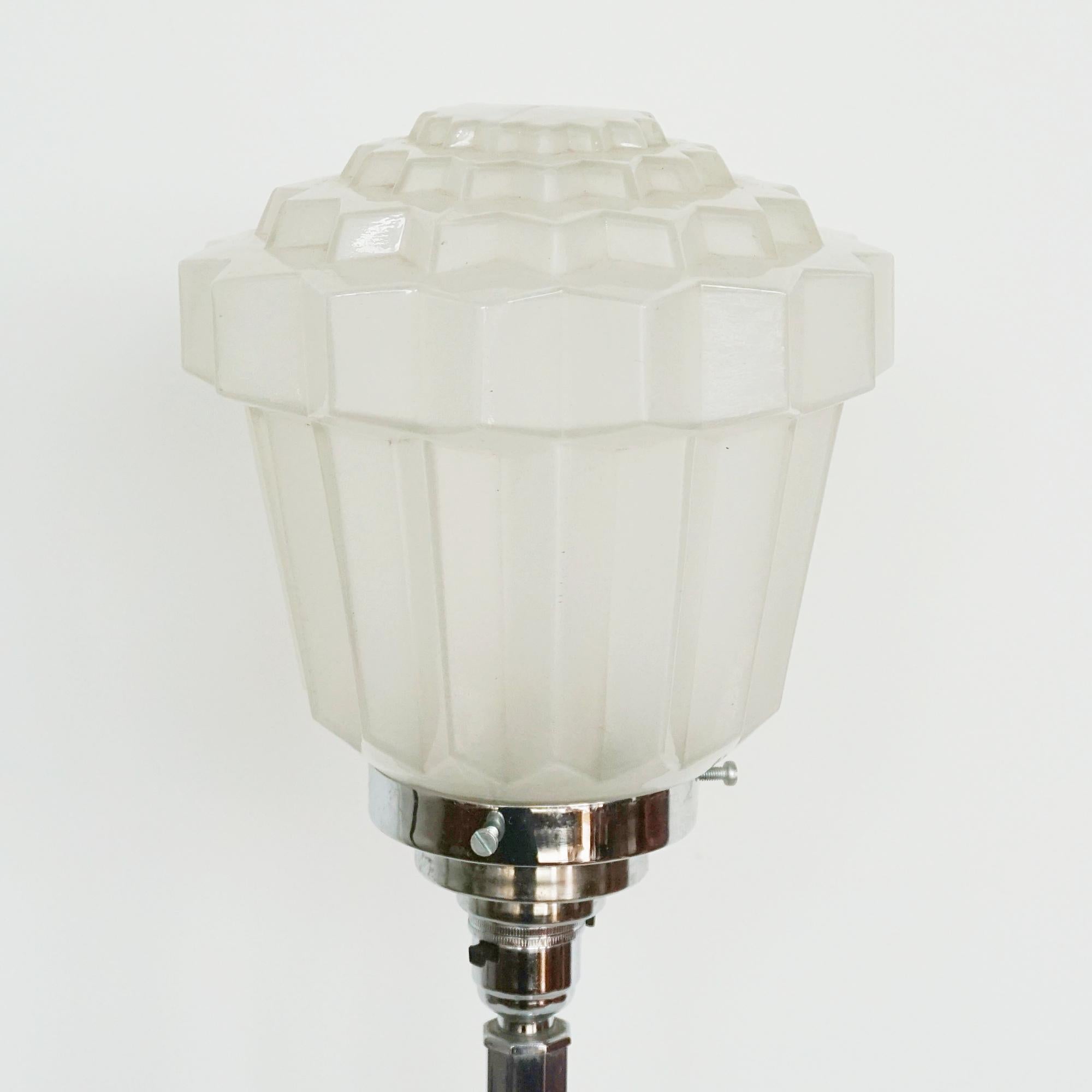 Lampe de table Art déco. Tige en métal chromé avec une base rectangulaire en métal chromé et un abat-jour en forme de gland en verre blanc dépoli. 