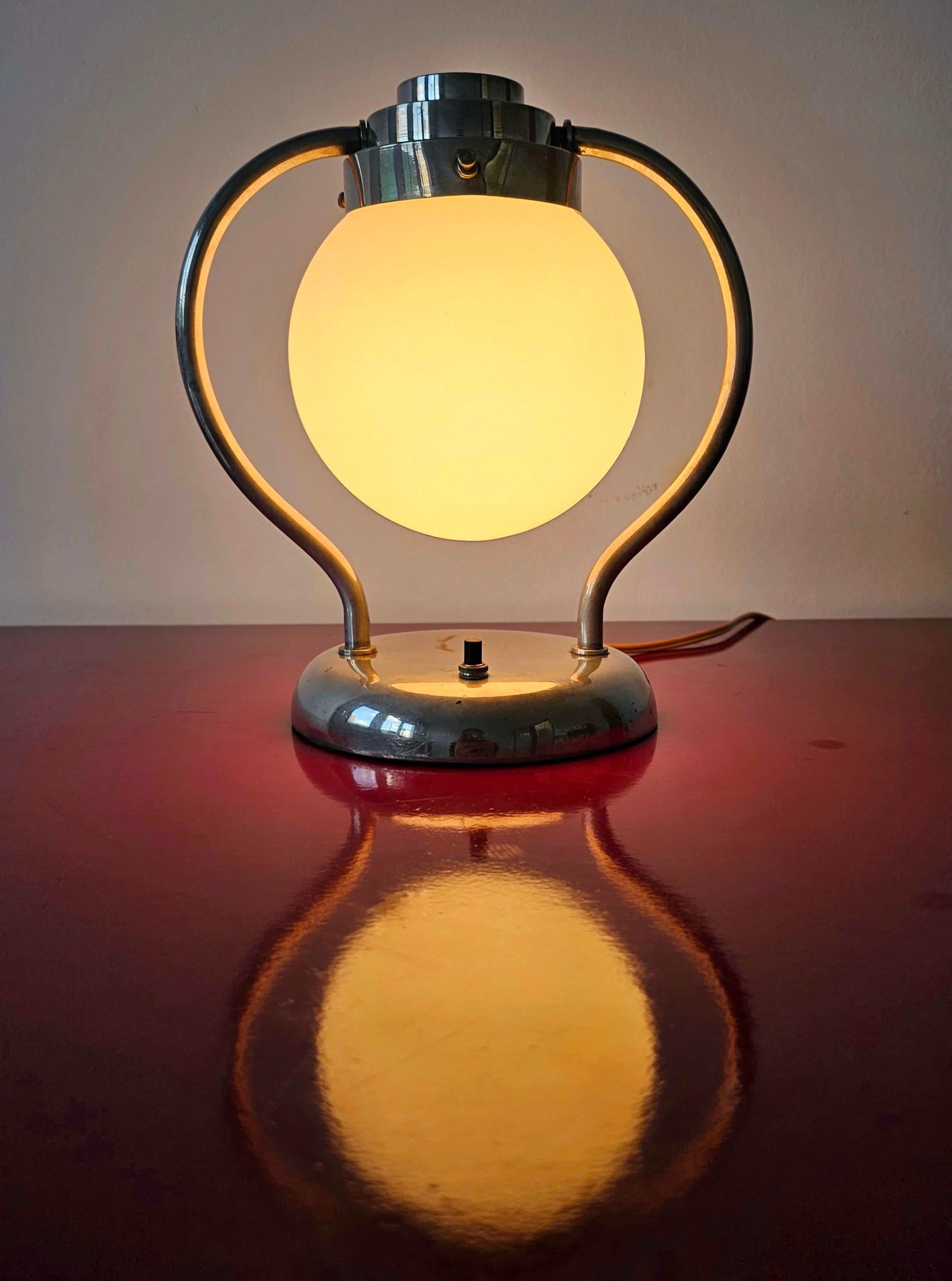 In diesem Angebot finden Sie eine sehr seltene Art Deco Tischlampe. Sie verfügt über einen verchromten Stahlfuß mit einem kugelförmigen Schirm aus Milchglas. Der Schirm und seine Halterung sind drehbar. Hergestellt in Deutschland im Jahr 1930.

Sehr