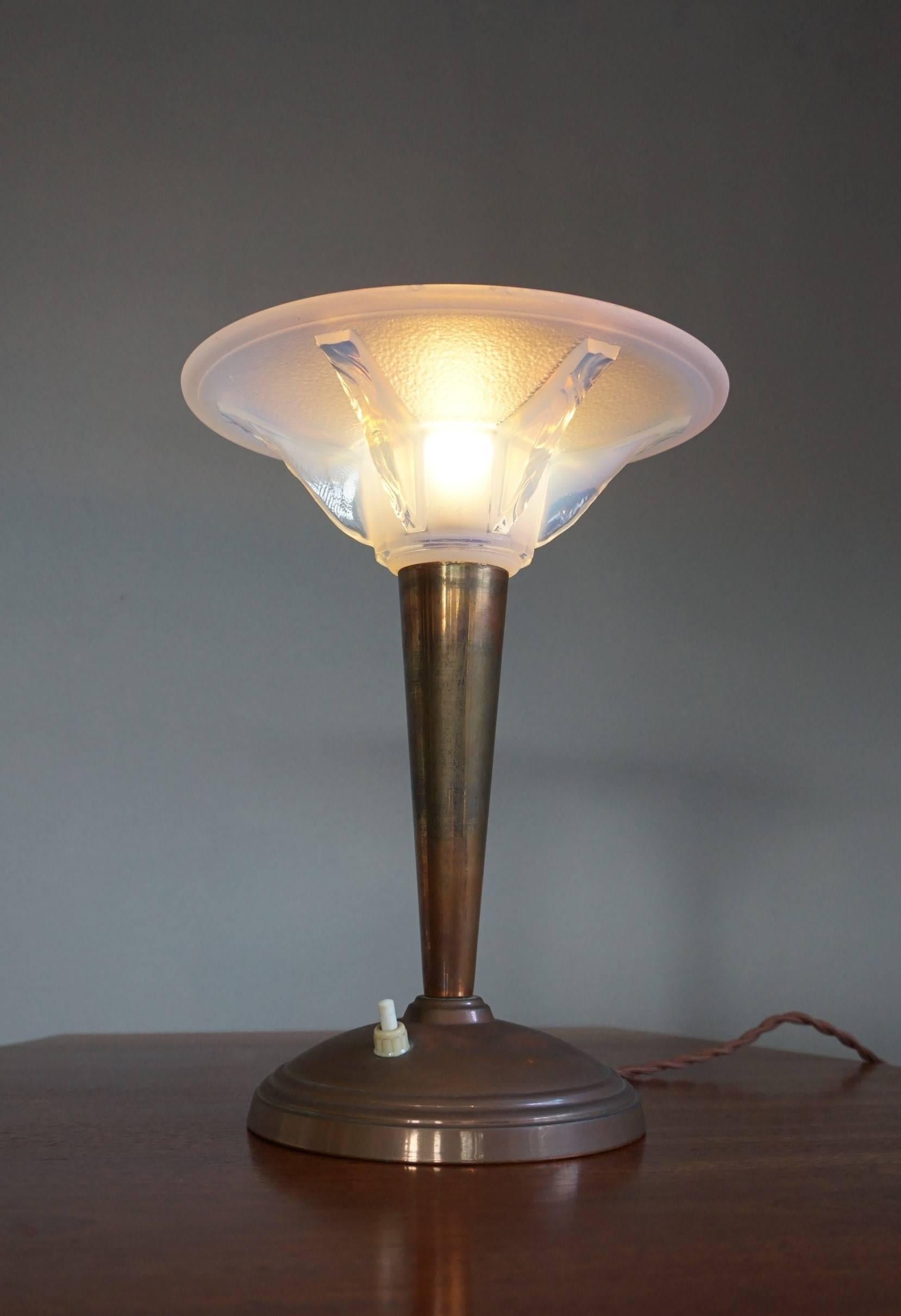 Rare 1920s brass lamp with a René Lalique style shade.

Thanks to the stunning glass shade this table or desk lamp radiates the most beautiful light imaginable. The design is simply breath taking and the combination of the patinated brass and the