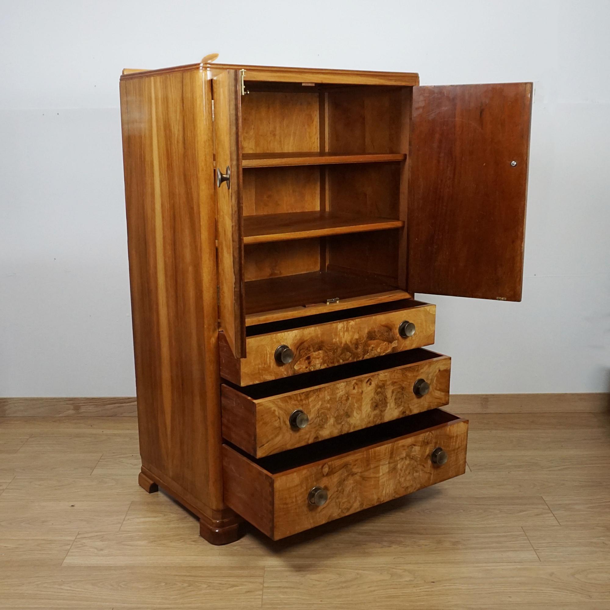 Ein Art-Deco-Tallboy aus furniertem Wurzelholz. Drei untere Schubladen mit oberem Schrankfach, das sich öffnen lässt, um Innenregale freizulegen. Gratnussbaum furniert mit originalen Metallgriffen. 
