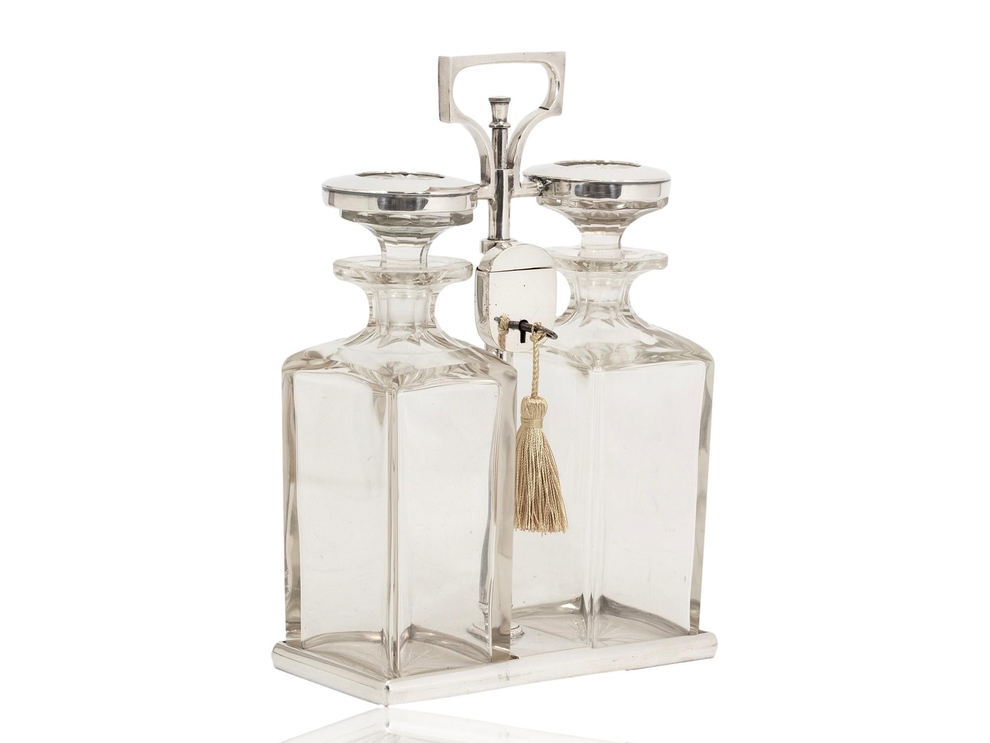  Art Deco Circa 1925

The Tantalus modelled with two hand-cut decanters locked into place by a silver plate frame. The frame with loop handle to the top which opens upon unlocking and lifts up and round to release the decanter bottles. Each glass