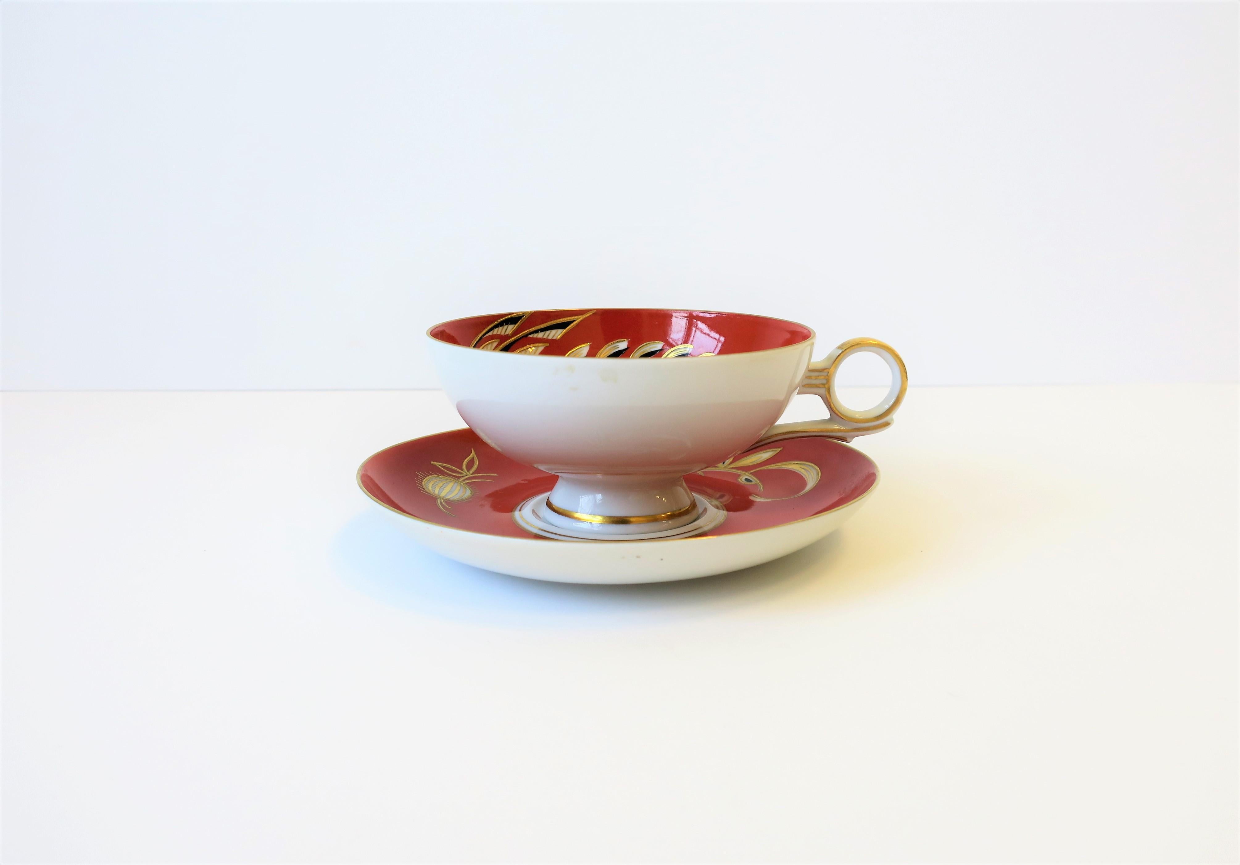 A beautiful porcelain Art Deco coffee or tea cup and saucer, Germany, circa 1960s. Design and colors include: white, terracotta, black and gold - with an elaborate bird design in a raised gold relief that's hand applied. With marker's mark on bottom