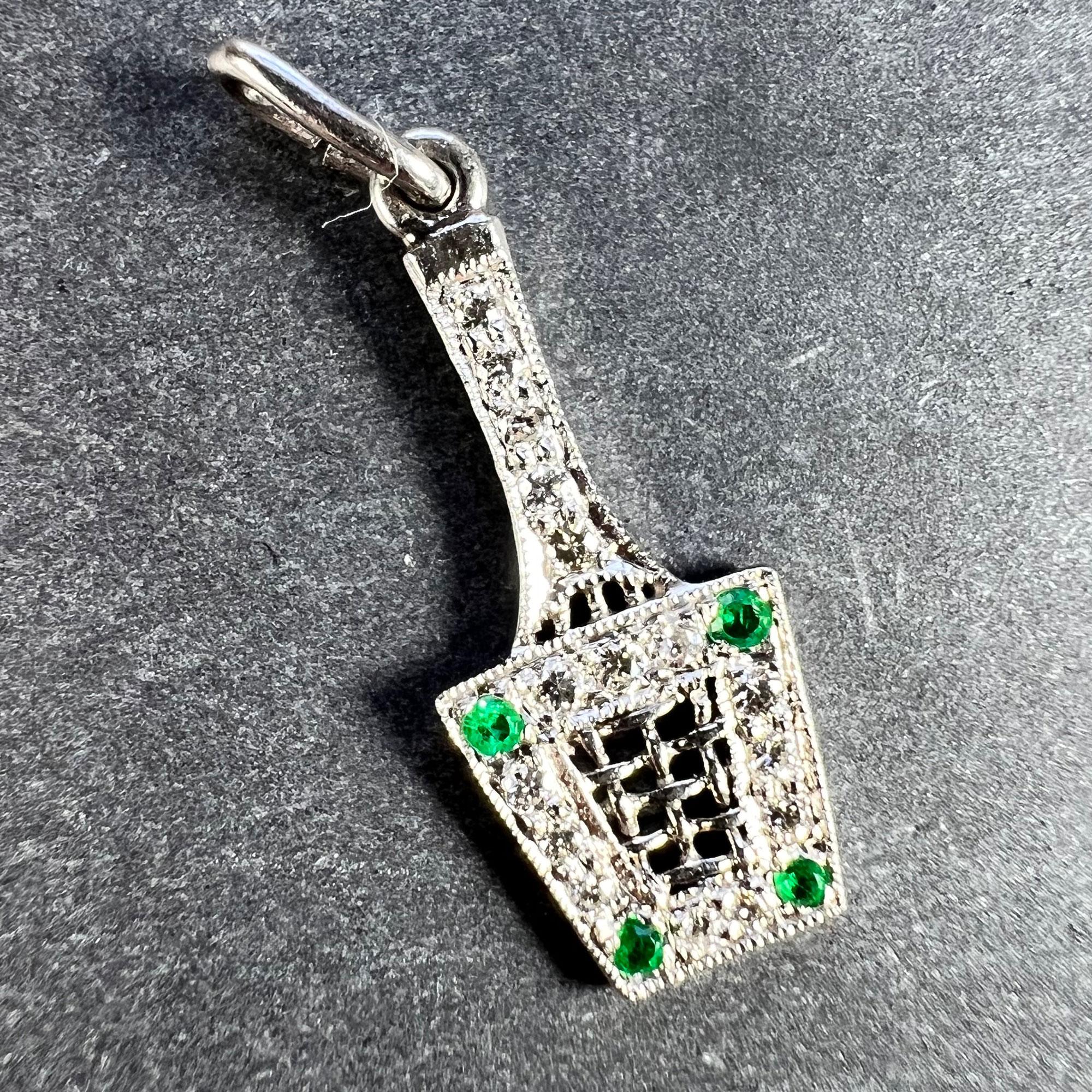 An Art Deco platinum charm pendant designed as a tennis racket in a press, set with 16 round brilliant cut white diamonds and four single-cut green emeralds. Unmarked but tested for platinum.

Gemstone weights: 
Diamonds: 0.32 carats (approximate