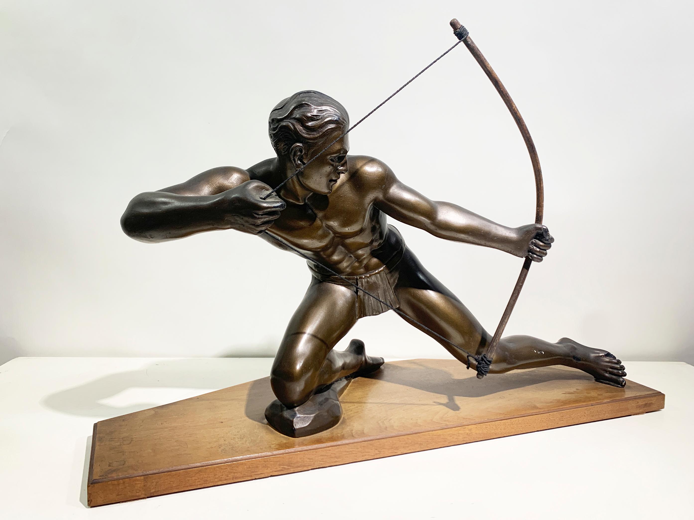 This sculpture depicts of a muscular archer in a dynamic pose, pulling back the string of a bow while preparing to release an arrow. The figure is kneeling on one knee, with the other leg extended behind for stability. His face exhibits a focused