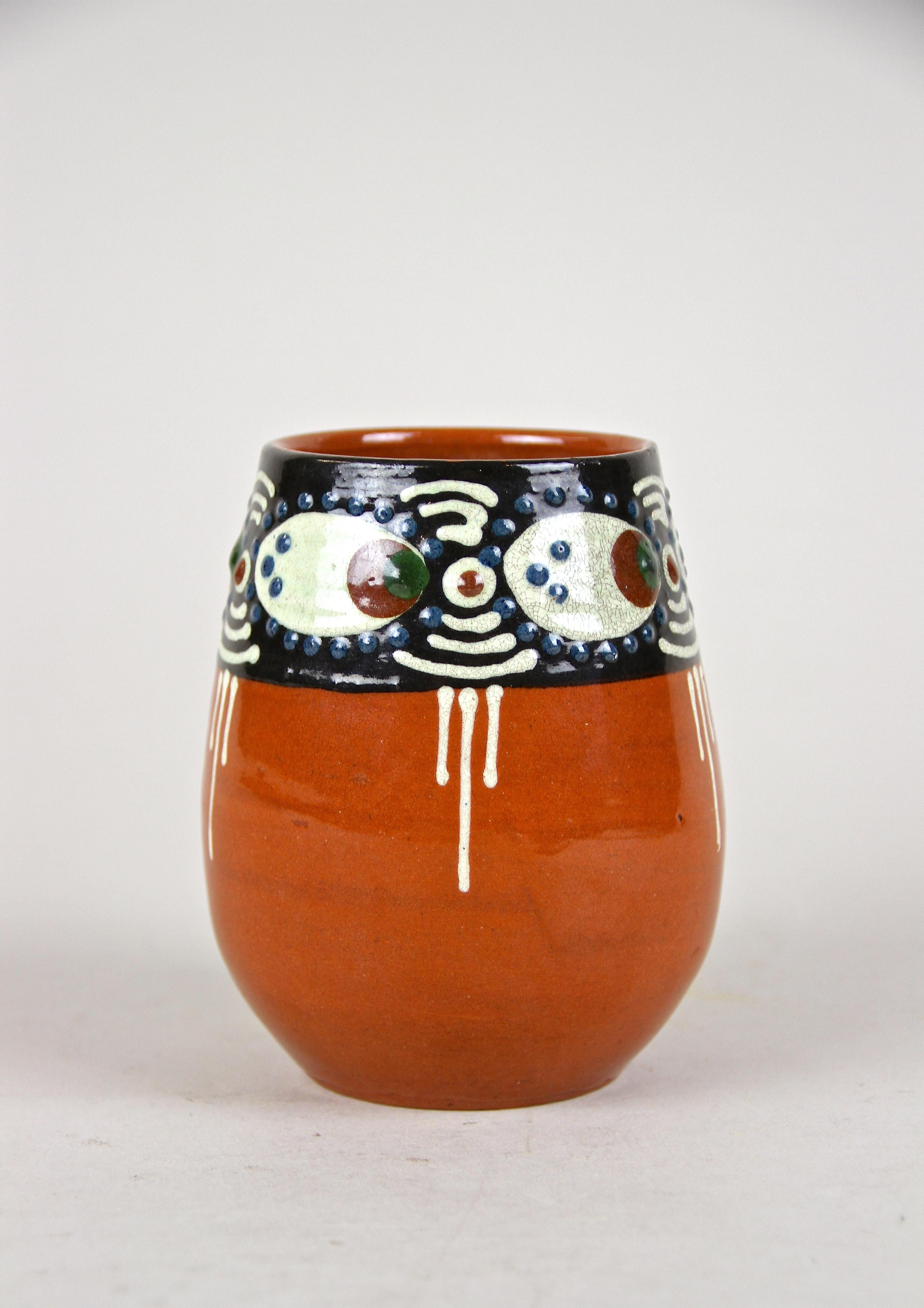 Small, decorative Art Deco terracotta vase with enamel paintings out of Austria, around 1920. The glazed, orange body shows a lovely design around the top, adorned by beautiful enamel paintings looking like eyes.