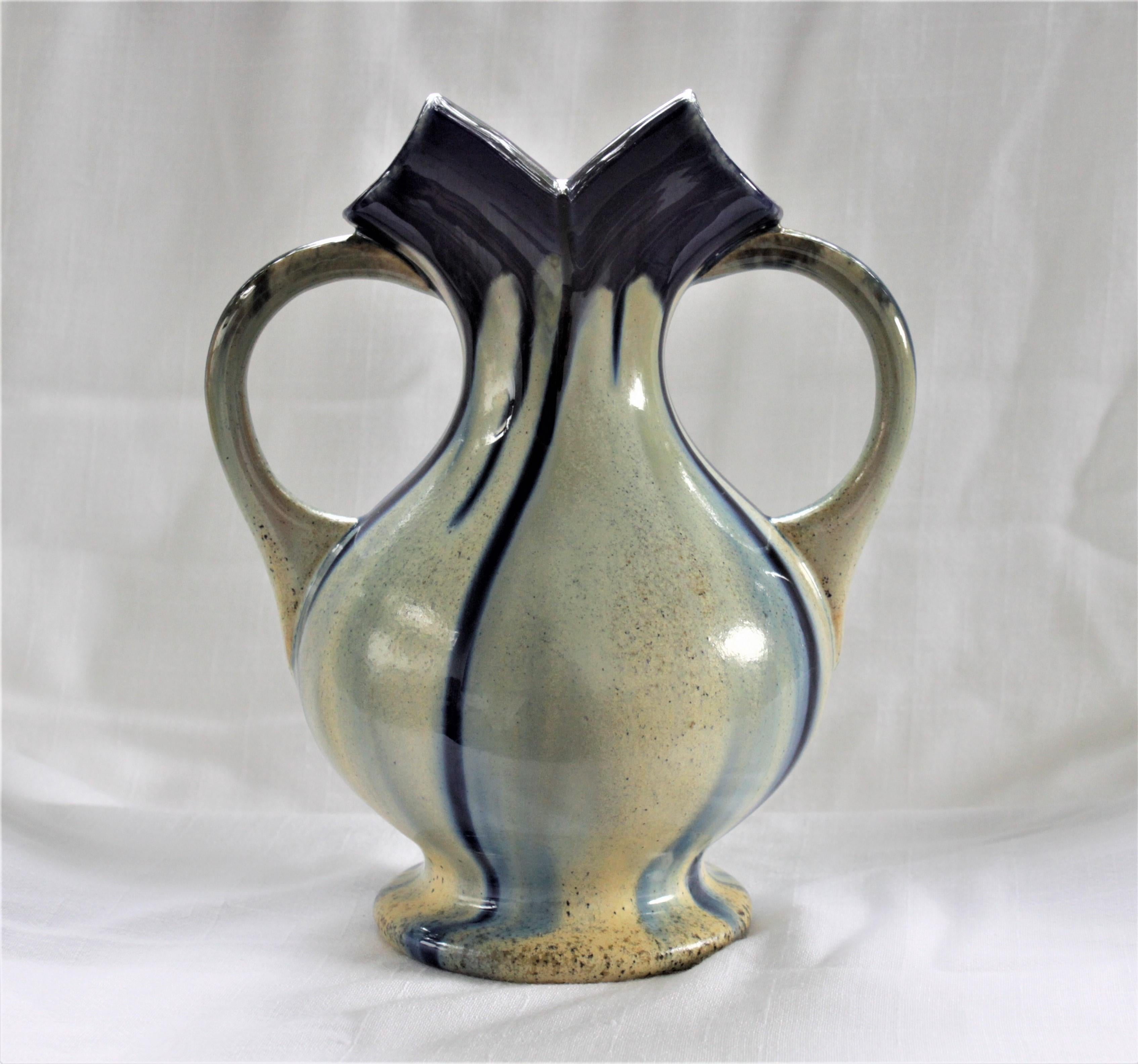 This double handled wedding vase is attributed to the Faincerie Therin Pottery Company of Belgium and dates to the Art Deco period. The vase is done in a brown earthenware pottery with a cream over-glaze and a cobalt blue and brown drip glaze. This