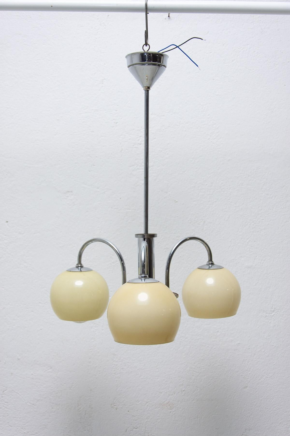 Art Deco three-armed chandelier with three curved chrome arms, shades in yellowish glass, manufactured approximately 1930´s in the former Czechoslovakia. New wiring.

Size: Height: 56 cm

Diameter: 41 cm

Lamp shade: 11 cm.