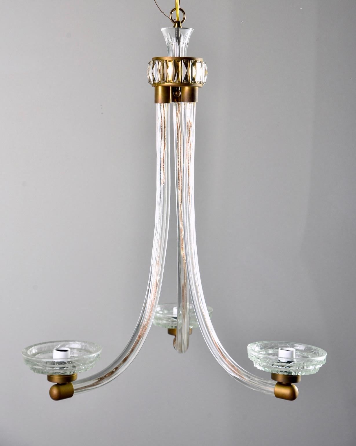 Art Deco / Modernist three-light chandelier features subtly curved clear glass arms with brass hardware, circa 1940. Etched glass bobeches and ceiling cap, faceted crystals surround the top brass cap. Three candelabra sized sockets. New wiring for