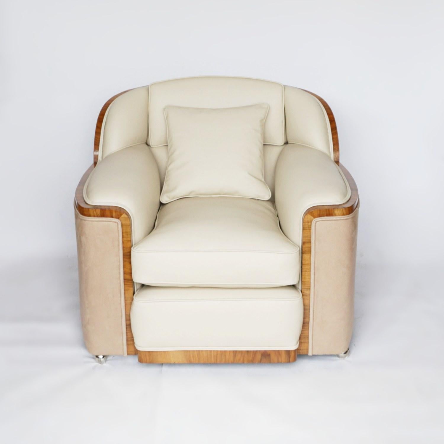 An Art Deco three-piece bankers suite by Harry & Lou Epstein, comprising of a three-seat sofa and pair of lounge chairs. Figured walnut banding, re-upholstered in cream leather and Alcantara oatmeal suede.

Dimensions: Sofa, H 83 cm, W 185 cm, D