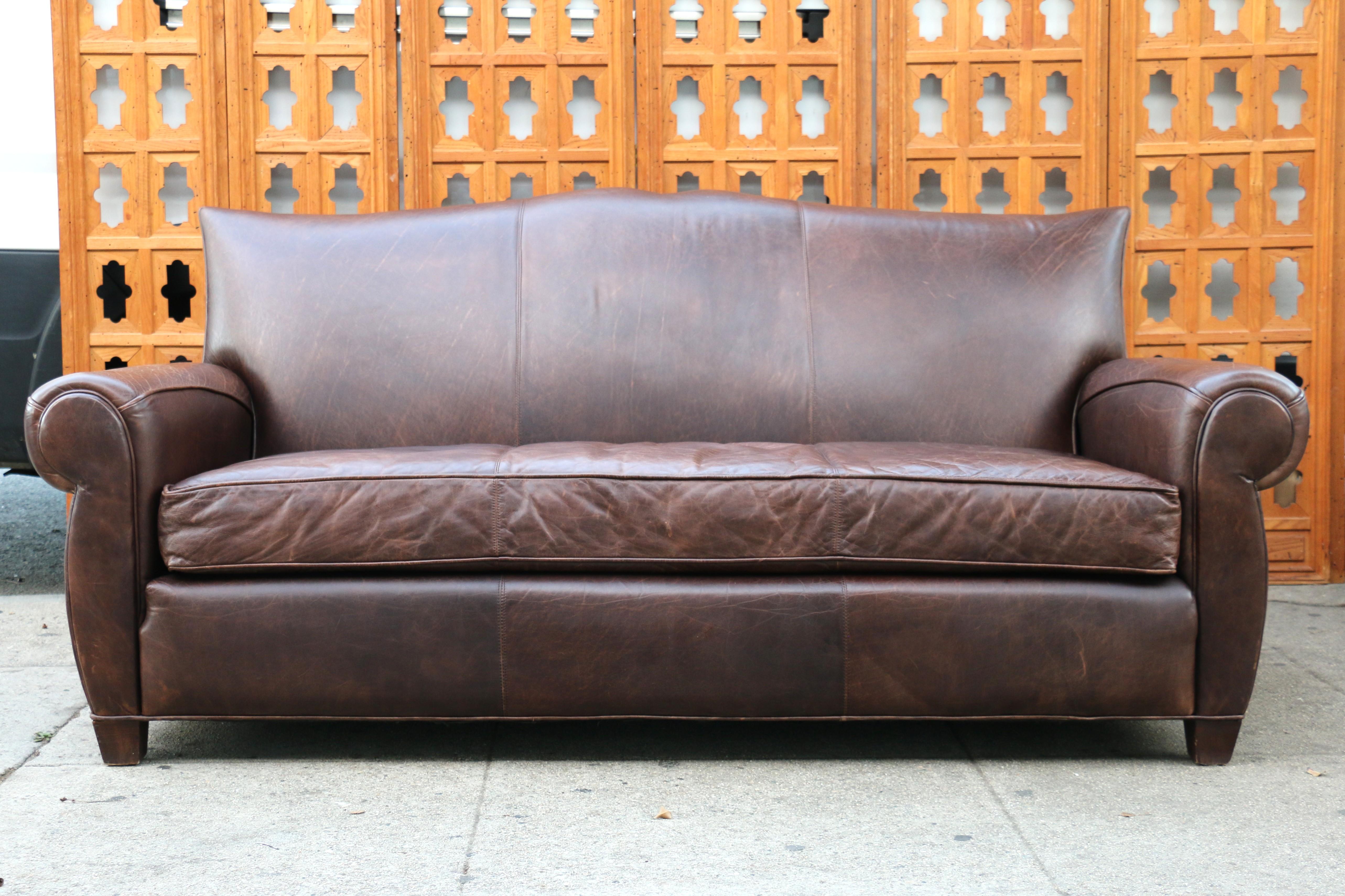 Spectacular Art Deco three seats sofa made of brown distressed leather and with a mustache shape. Absolutely comfortable sofa. Very sturdy and strong. Really good condition and great looking.