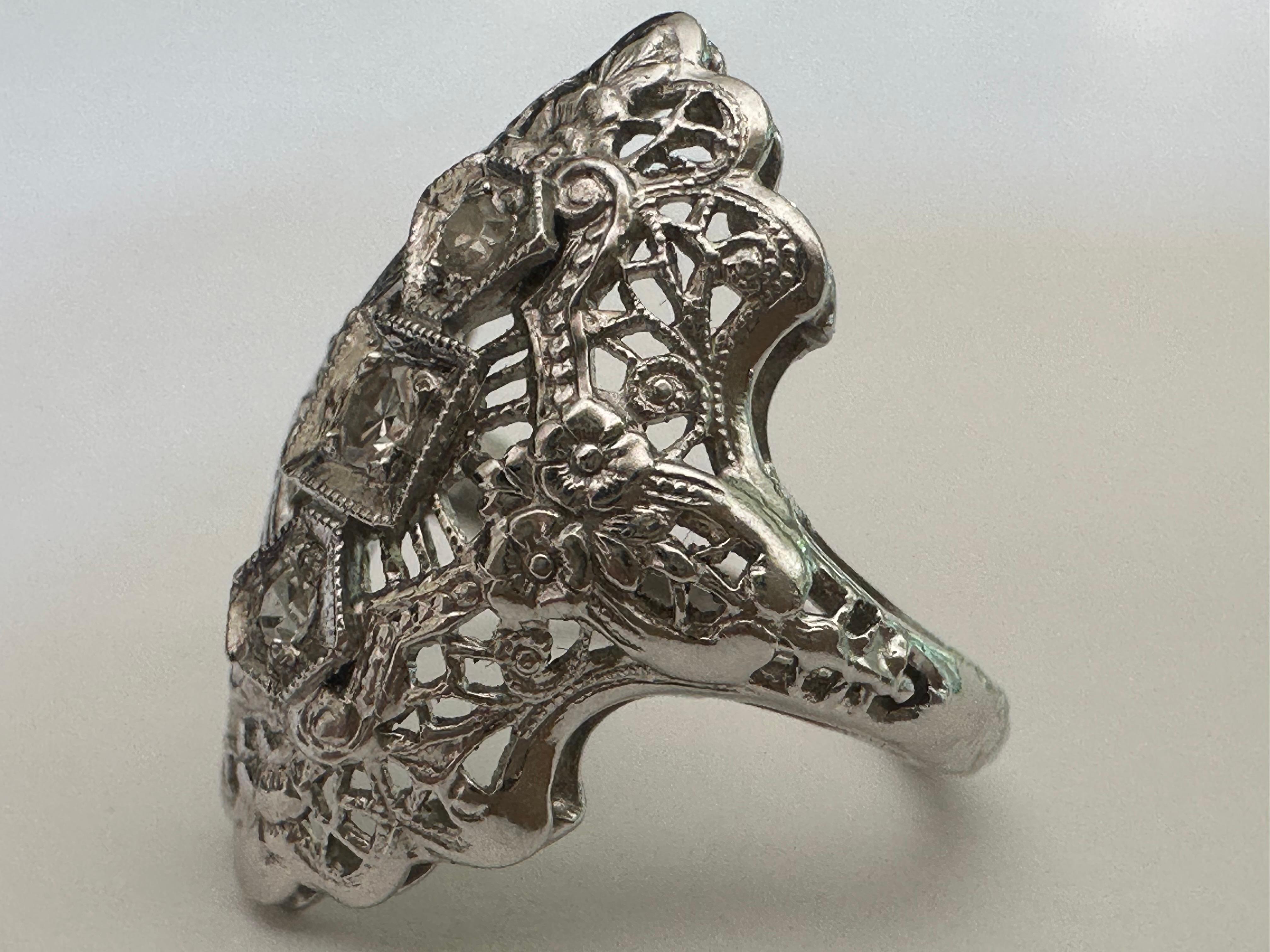 This striking Art Deco band, with its north-south orientation, is meticulously crafted from 14K white gold with fine filigree details and set with a trio of single cut diamonds totaling approximately 0.10 carats. 