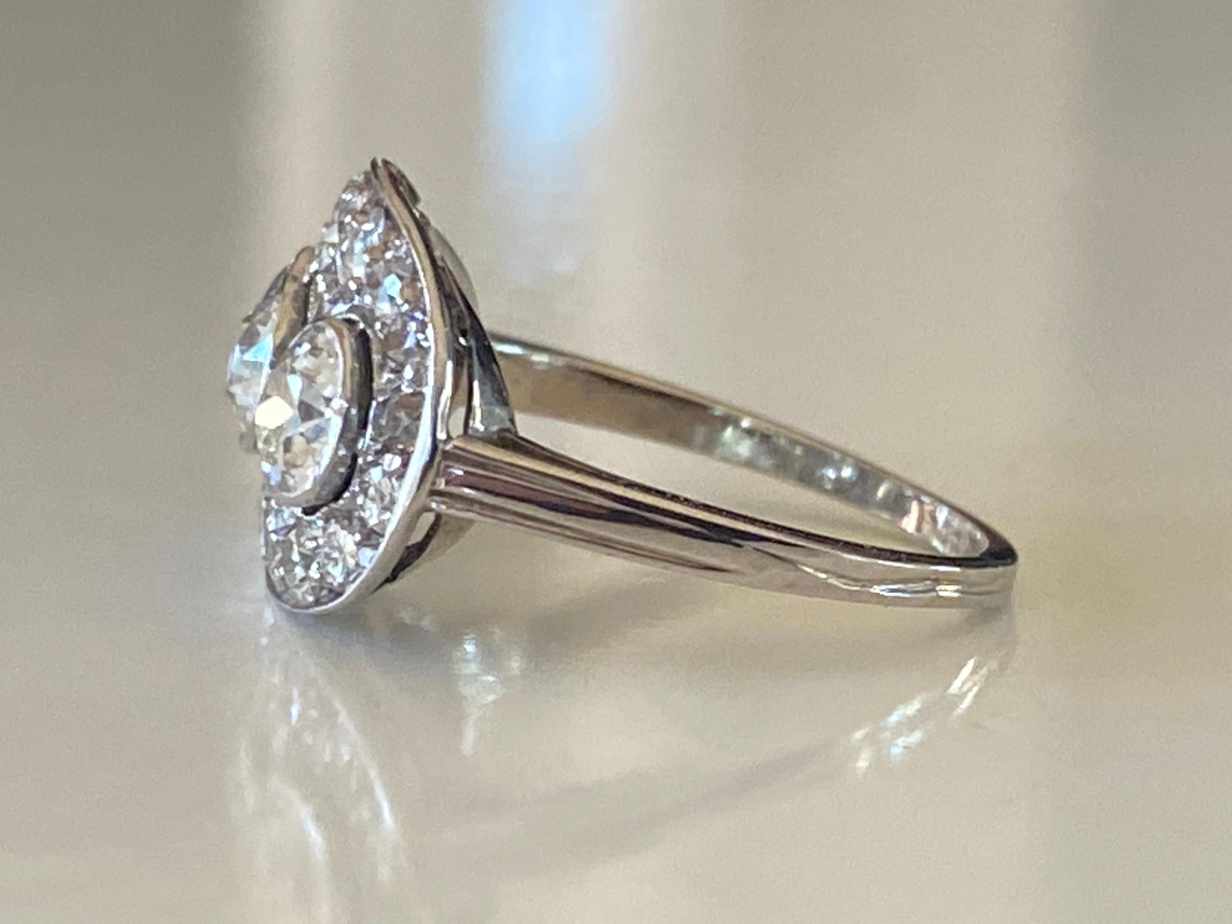 Crafted in the 1930s in platinum, this glistening Art Deco ring features three Old European cut bezel-set diamonds (totaling approximately 1.25 carats, 
G-H color, VS-SI clarity) surrounded by eighteen smaller Old European cut diamonds (totaling