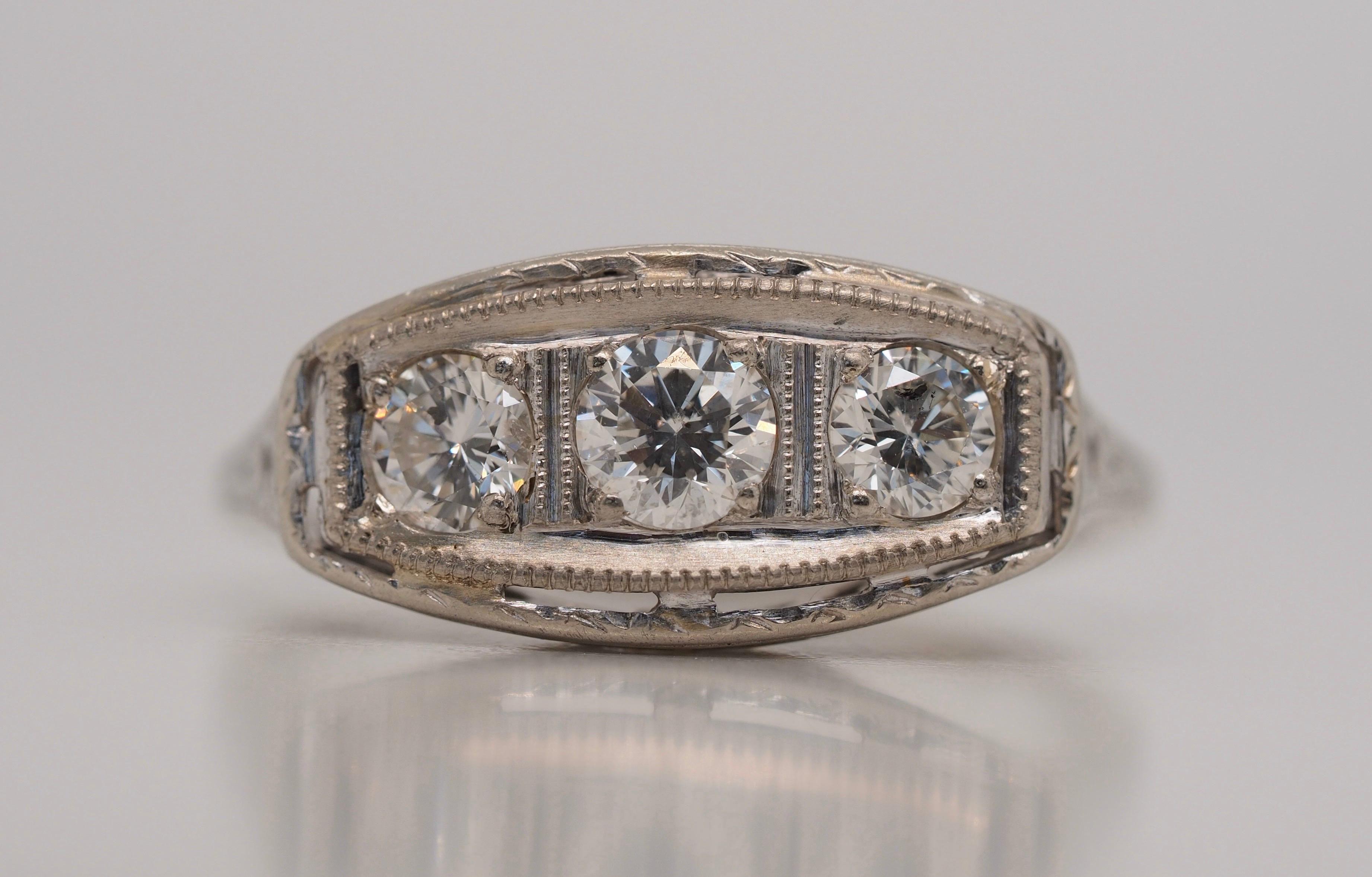Art Deco Three-Stone Diamond Engagement Ring in 18 Karat Gold dates back to the 1920's with its incredible and notable design. Round brilliant cut diamonds were born in 1919 and is what is set in this marvelous ring. The center diamond weight is