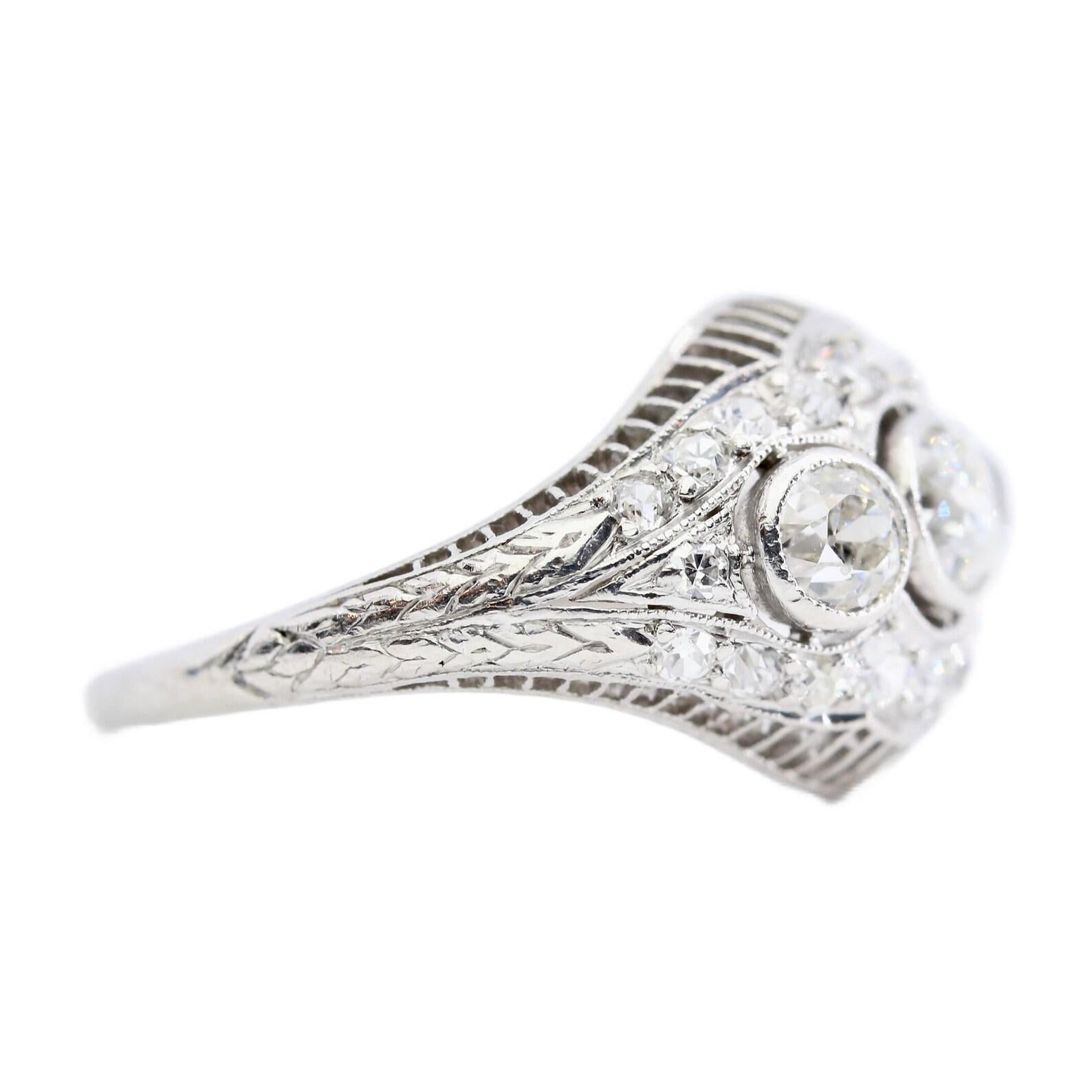 An Art Deco period three stone diamond ring crafted in platinum.

Centered by a trio of bezel set old European cut diamonds of 1.05ctw with H color and VS clarity. 

Accented throughout by a further 0.60 carats of pave set old European cut diamonds;