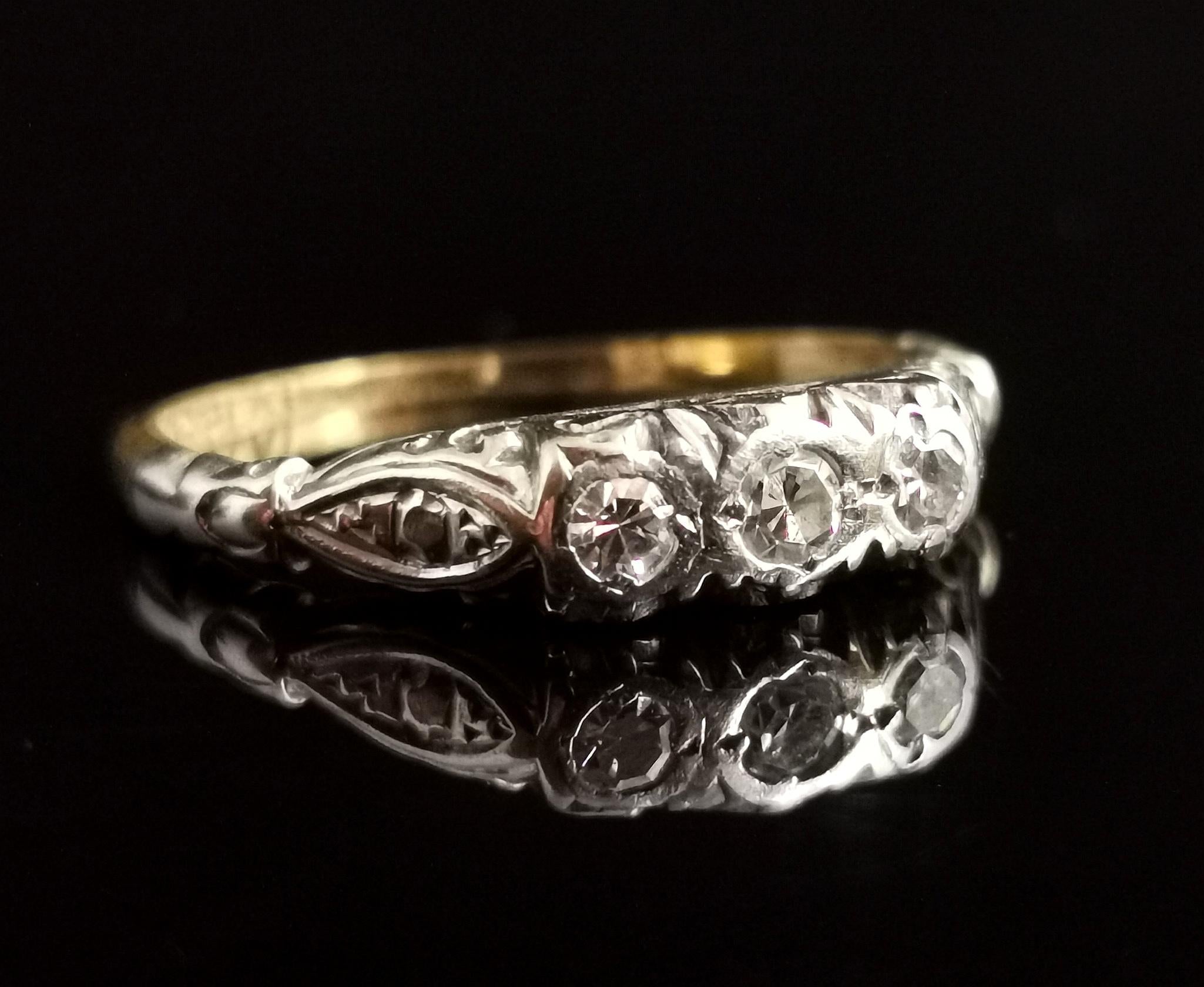 A pretty vintage Art Deco diamond, three stone ring.

A rich 18kt yellow gold band with a row of three sparkling single cut diamonds of approx 0.10 carats set into an illusion setting.

The diamonds are surrounded by the scrolling platinum design