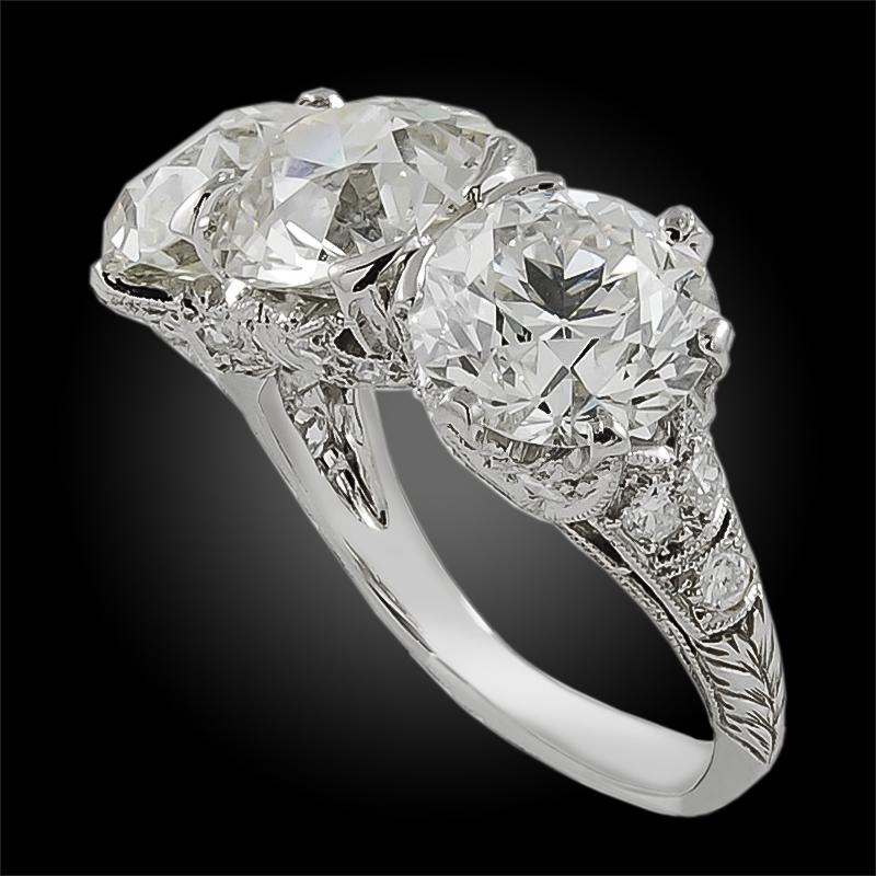 Art Deco Three Stone Diamond Ring in Platinum.

A vintage Art Deco three-stone ring with intricate ornamentation on side and front views, which are peppered with milligrain, engravings and intermittent round brilliant diamonds.

Diamonds: Approx.
