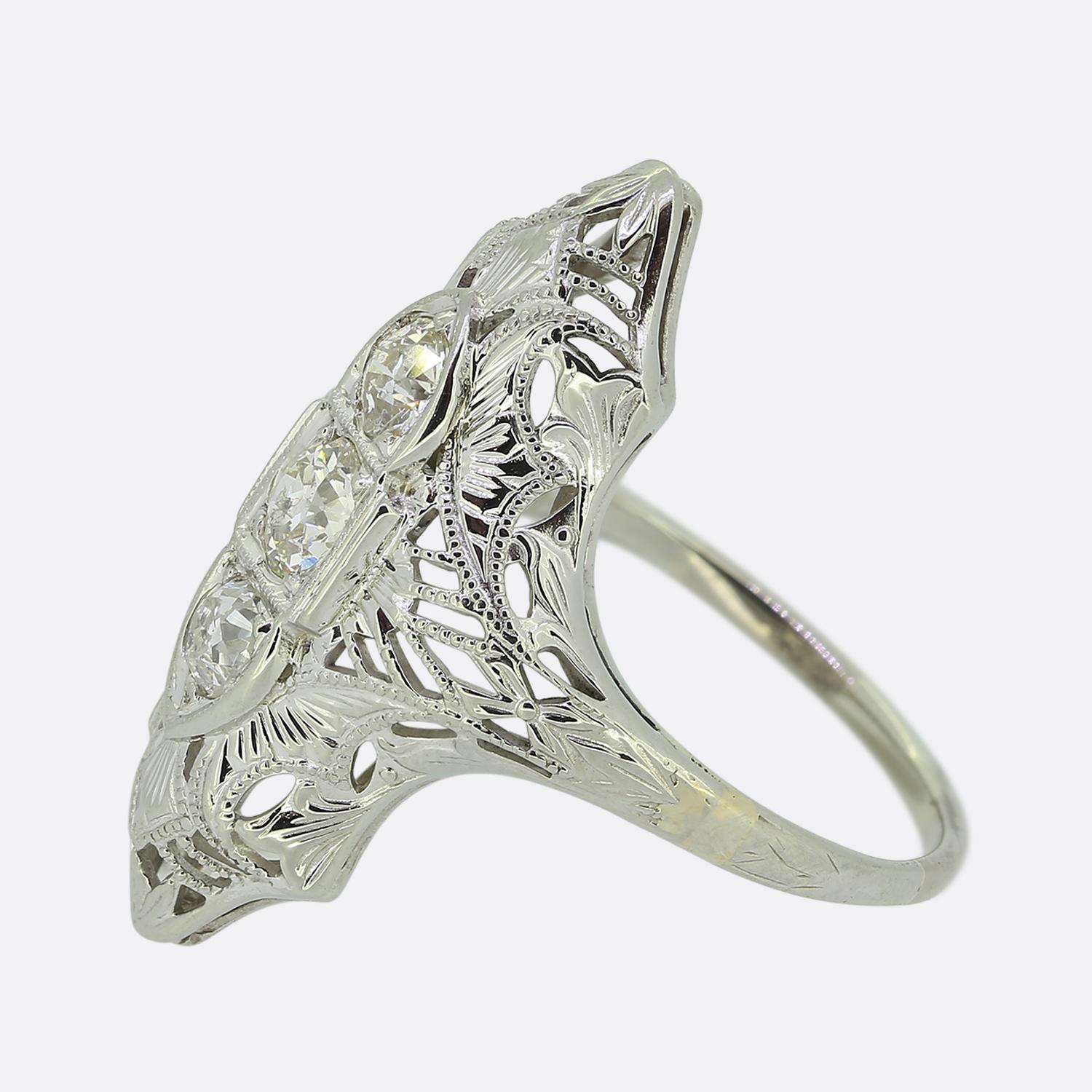 Here we have a delightful Art Deco three-stone diamond ring. Three round faceted old cut diamonds have been individually claw set atop of one another in a vertical fashion amidst a fine milgrain bordering at the centre of the face. This detailing