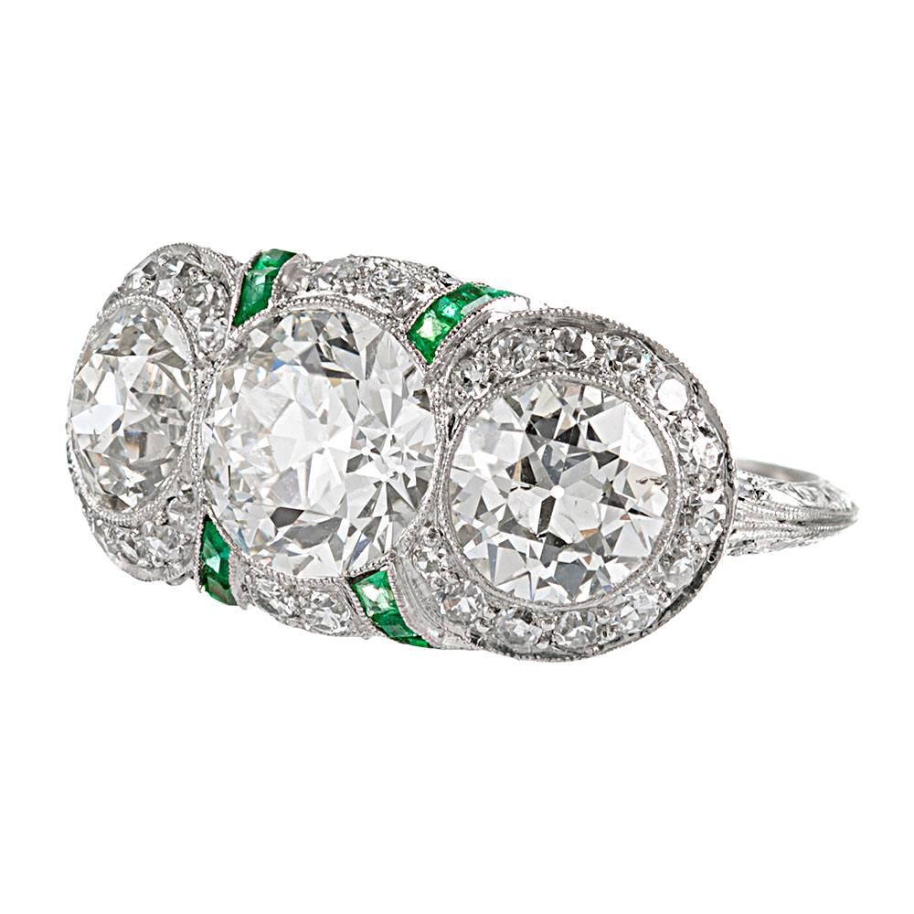 An exceptional creation, handmade in platinum and adorned with finery at every opportunity, this ring possesses a level of detail and design intricacy that is rarely seen in modern jewelry. The ring is centered upon three old European cut diamonds,
