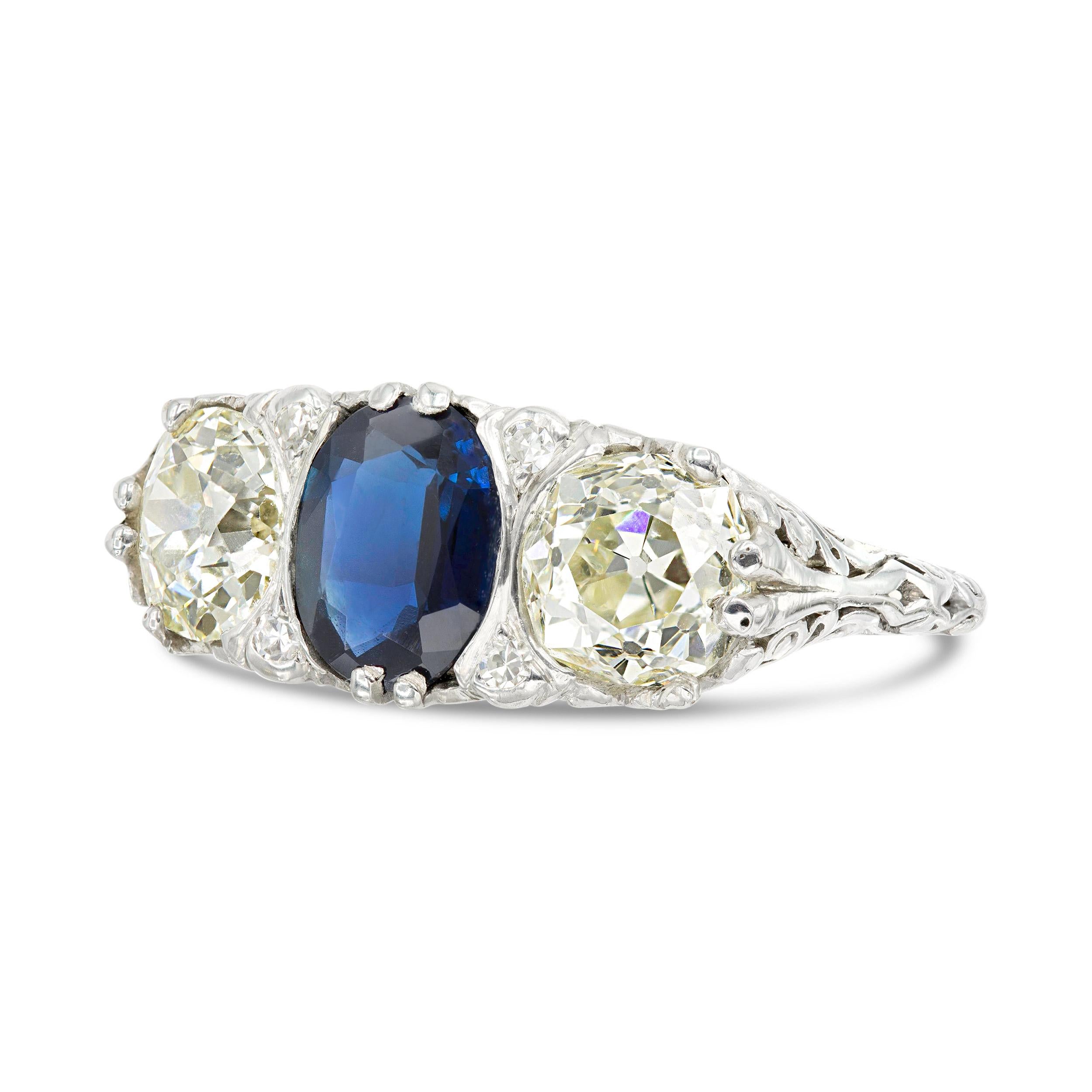An art deco trilogy ring that has oh so much character. A lush blue oval cut natural sapphire sits between two super classic looking old Euros weighting a little over a carat each. The trio is held by an old-world style filigree setting that offers
