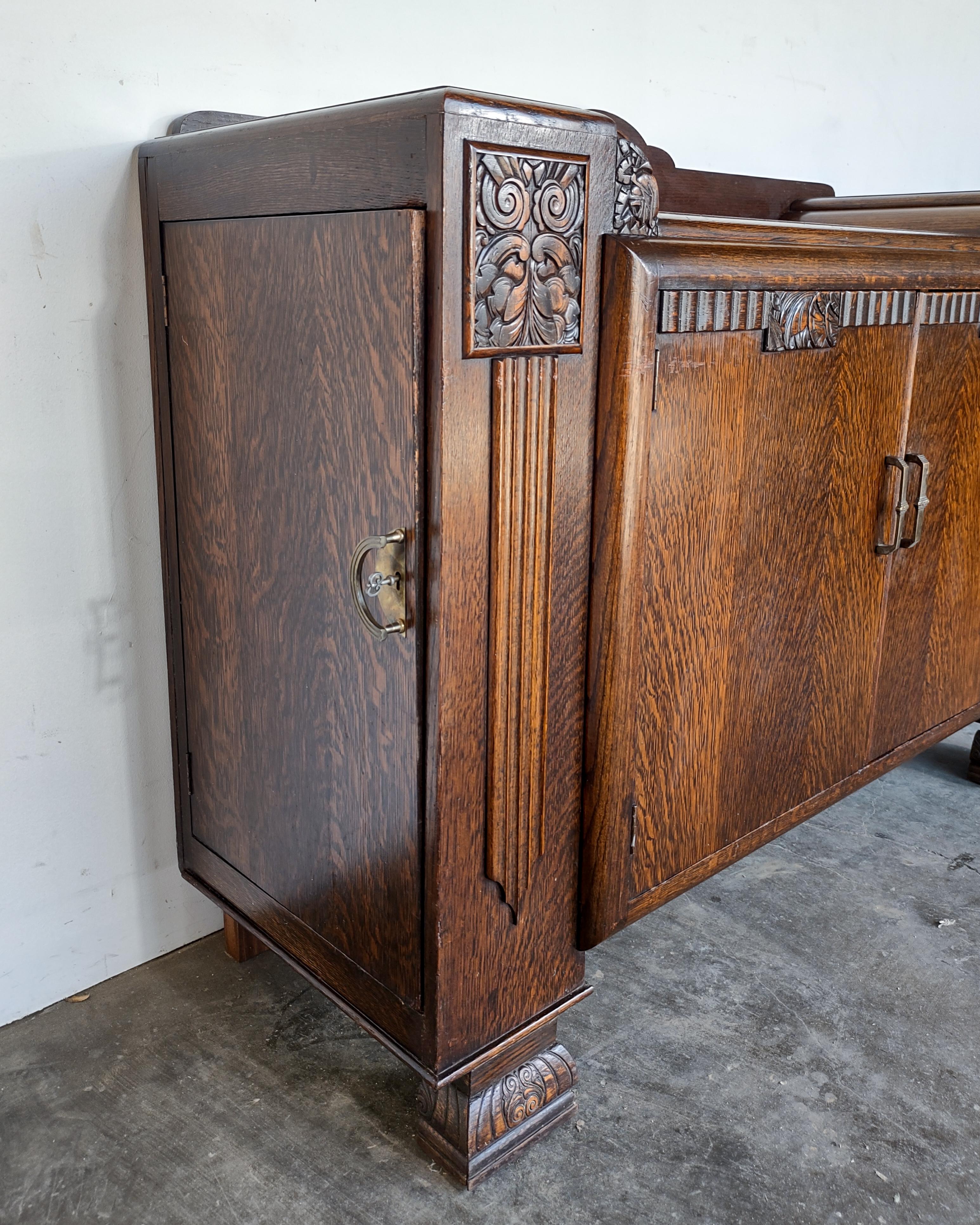Art Deco quarter sawn tiger oak cabinet. Stunning wood grain covering entire body and hand carved details. Interior features shelving areas and two drawers. Each side piece contains 