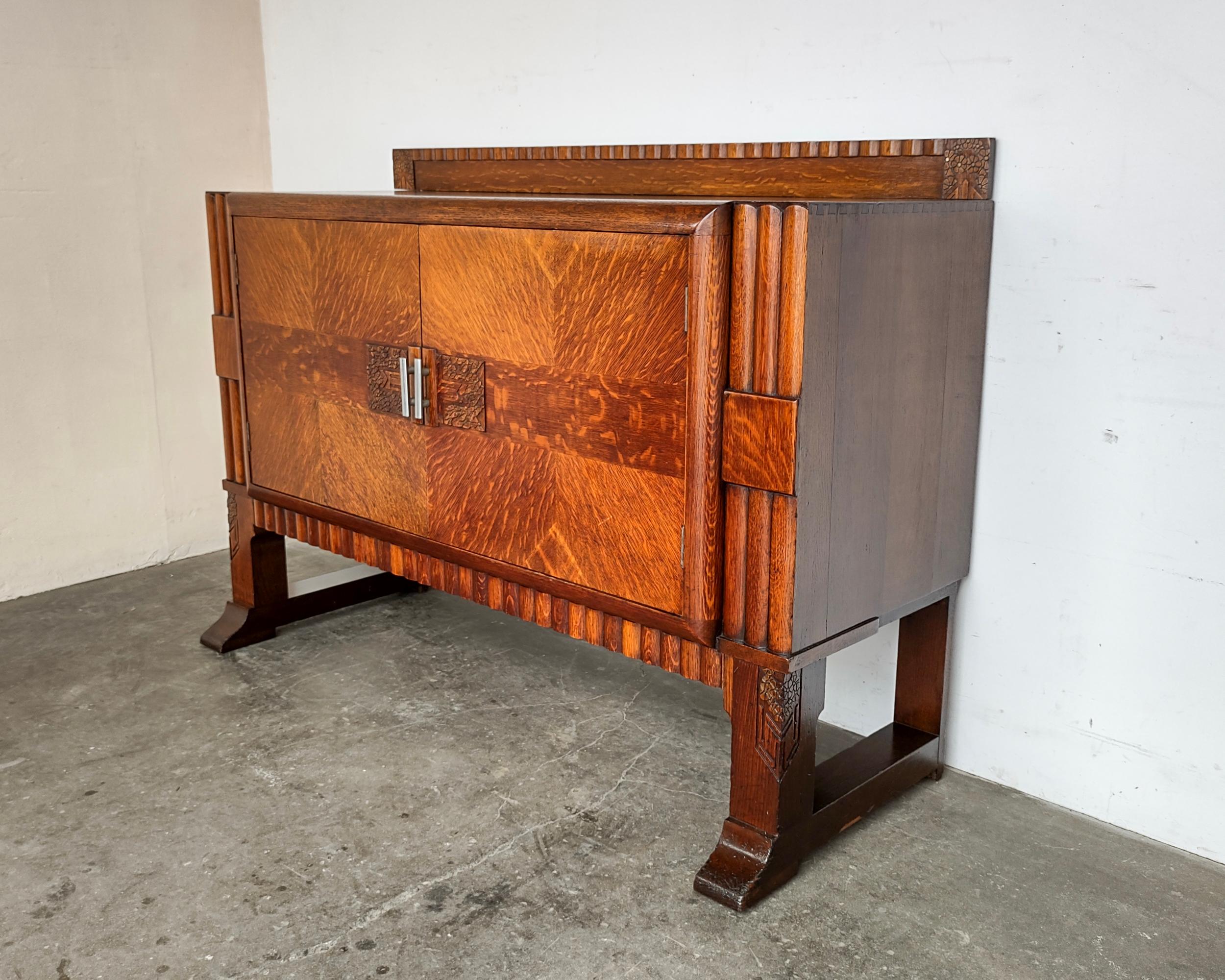 Beautiful Art Deco tiger oak cabinet. Book matched door with hand-carved details, scalloped designs throughout. Cabinet doors open to removeable shelves on each side and four small wooden drawers. Professionally restored. Great condition, some light
