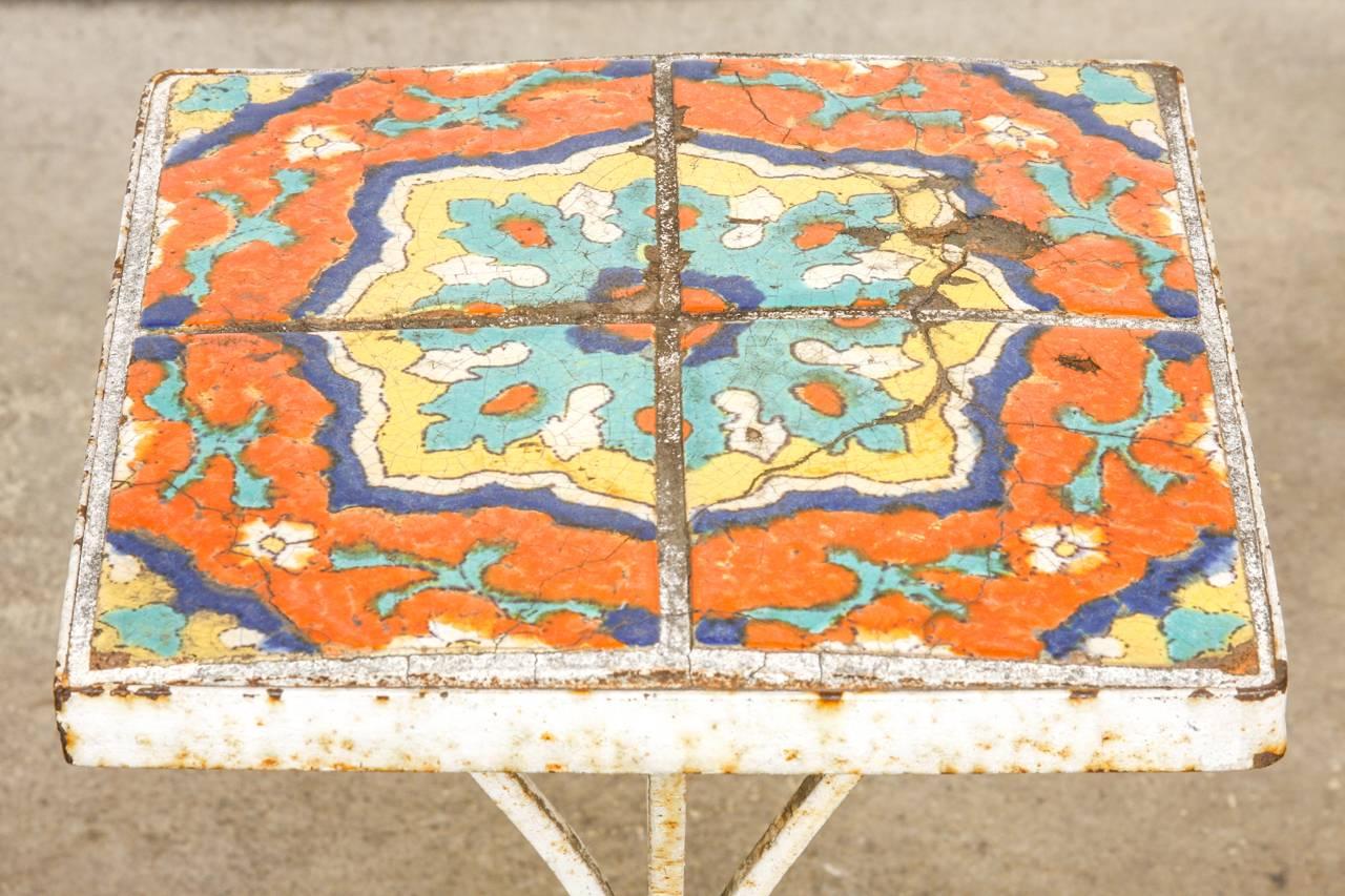 Elegant wrought iron and ceramic tile drinks table featuring hand-glazed decorative art tiles from Catalina, California. Made in the Art Deco style the iron base has four delicate curved legs that conjoin in the middle. The table has a lovely