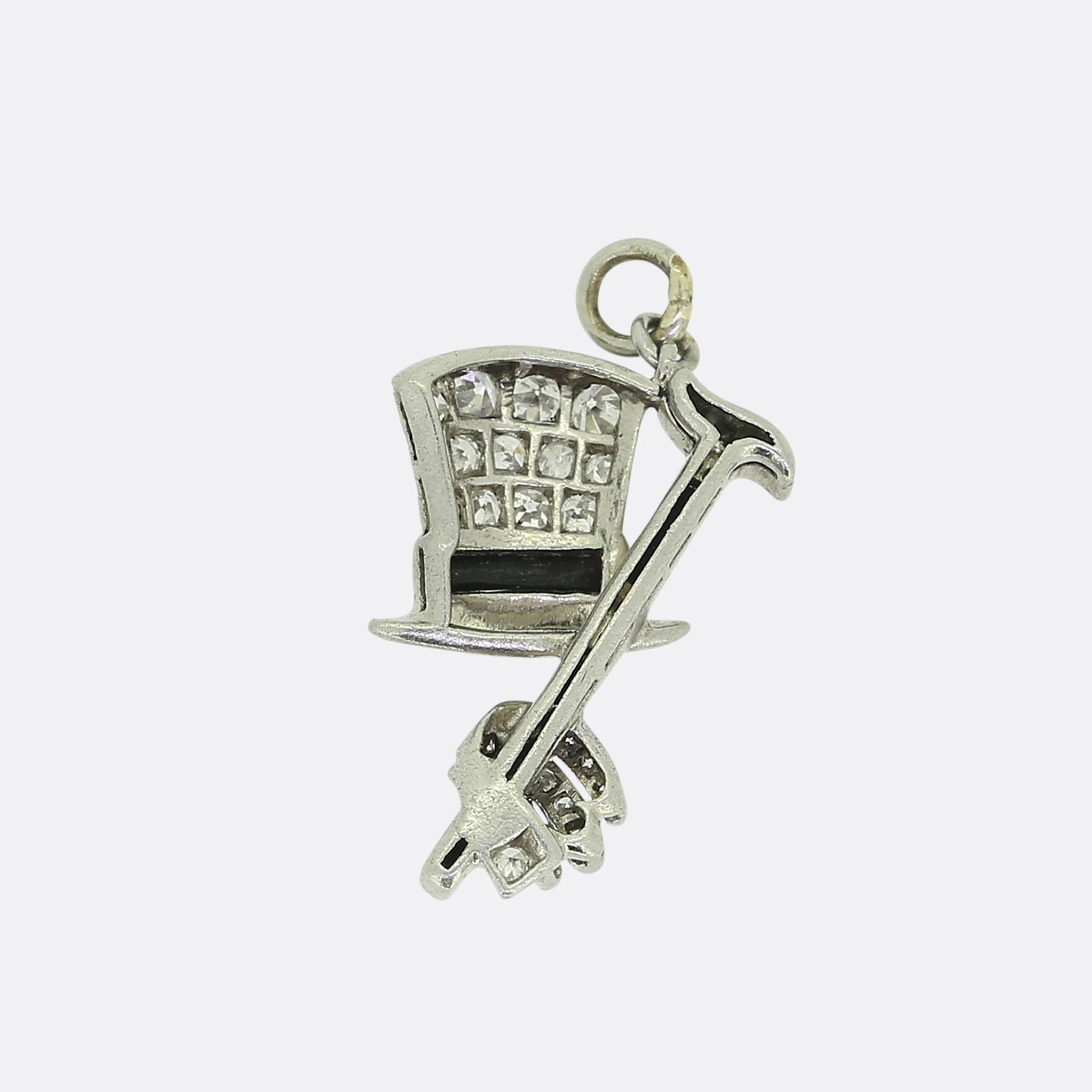 Si tratta di un dettagliato charm in platino con un cappello a cilindro e un bastone, ornato da diamanti bianchi a taglio singolo e finiture in onice nero. Il ciondolo mostra un'intricata lavorazione artigianale con un cappello a cilindro tempestato