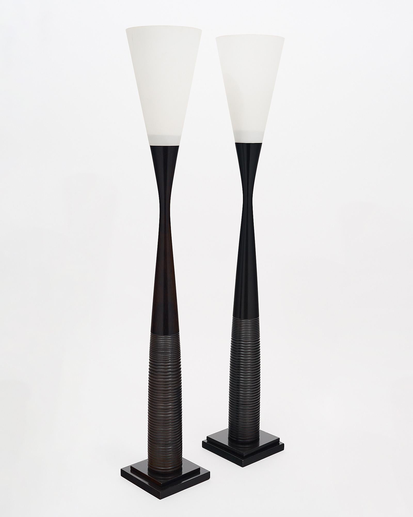 Pair of Art Deco Totem floor lamps from France. Each light features a turned wood base with the classic Art Deco details. Sitting atop each base is a conical white glass shade. This pair has been newly wired to fit US standards.