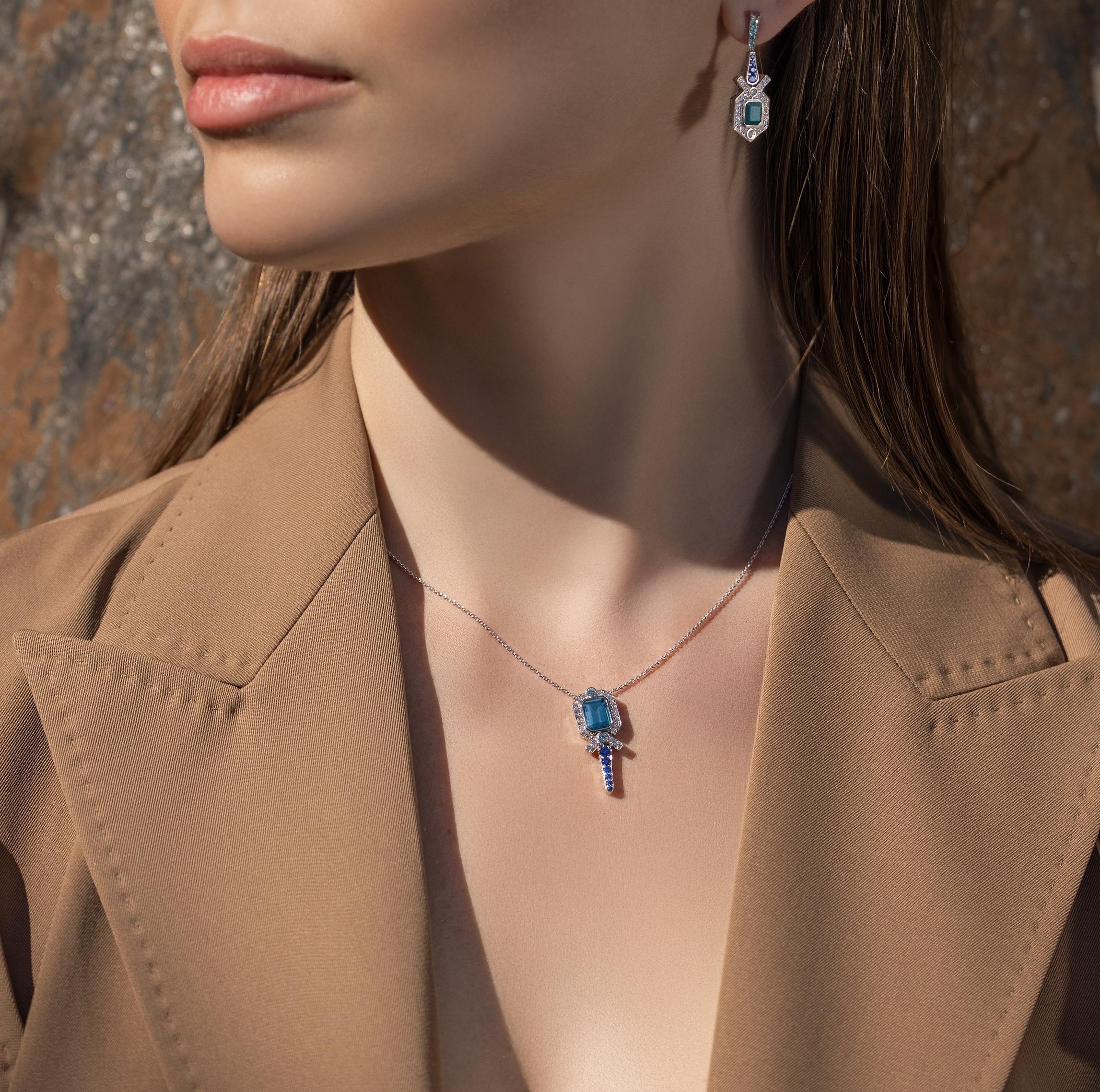 Die Atlantis-Halskette wird von einem strahlend blaugrünen Turmalin getragen, der von einem harmonischen Arrangement aus blauen Saphiren, Diamanten und kleineren Paraiba-Turmalinen eingerahmt wird. In Anlehnung an die Opulenz und Symmetrie des Art
