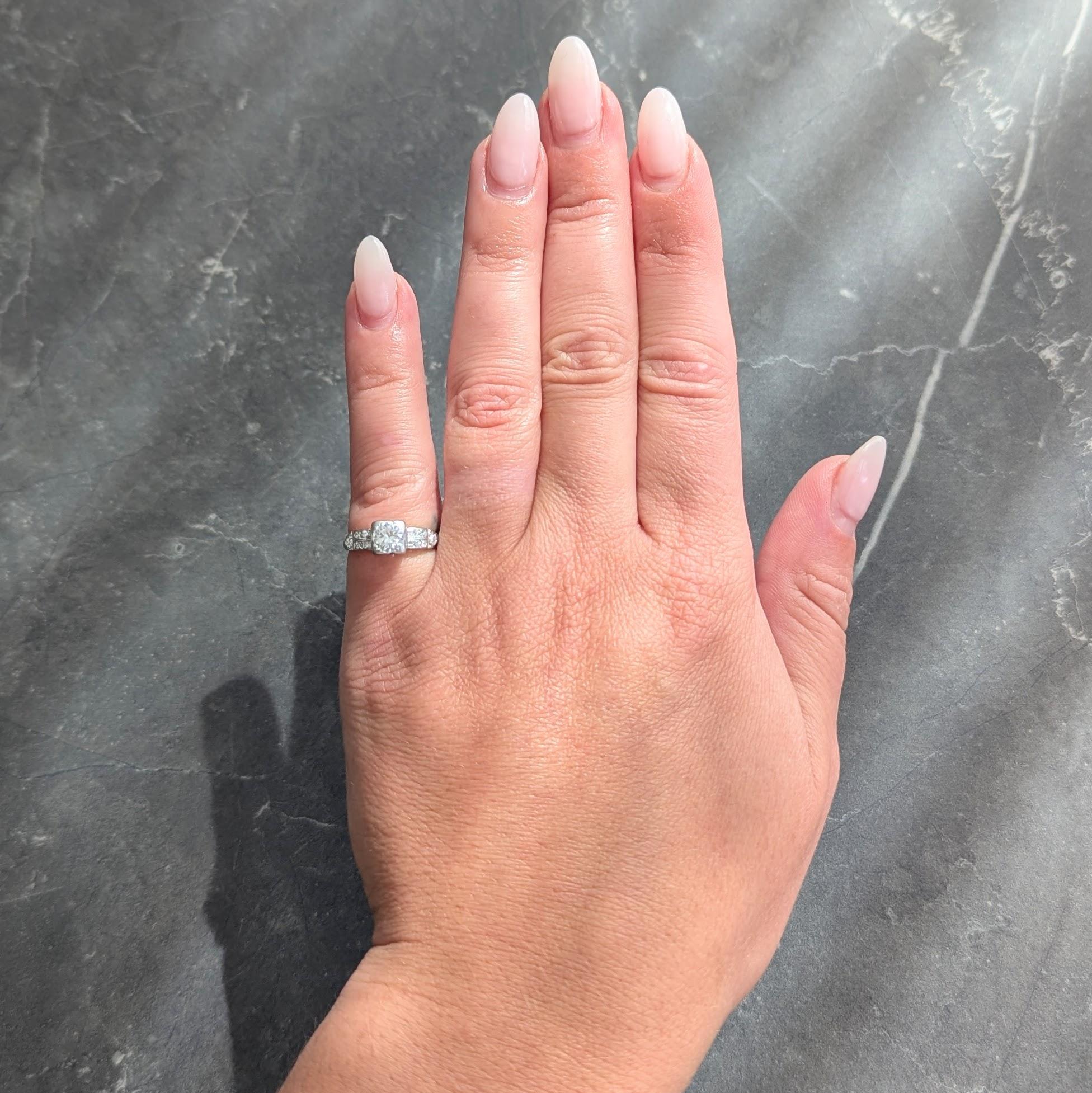 In der Mitte ein Diamant im Übergangsschliff mit einem Gewicht von etwa 0,50 Karat - Farbe G und Reinheit VS2
Perle in einem quadratischen Kopf, flankiert von gerillten Schultern mit Pfeilmotiv
Akzentuiert durch Reihen von perlenbesetzten Diamanten