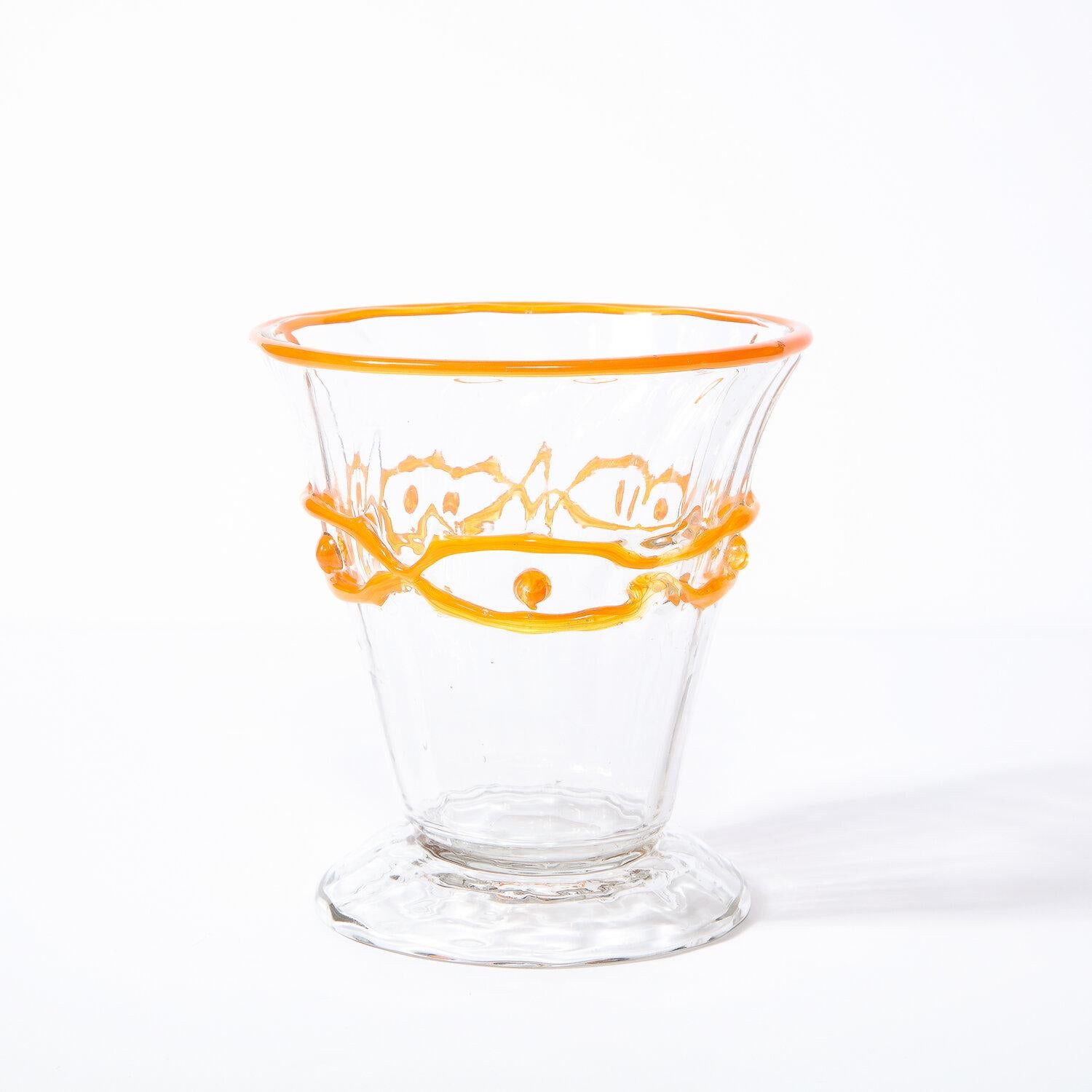 This refined Art Deco vase was realized and signed Daum Nancy in France circa 1920. It features a tapered conical body in translucent glass with a circular mouth adorned with tangerine accents and geometric detailing (in the same hue) circumscribing