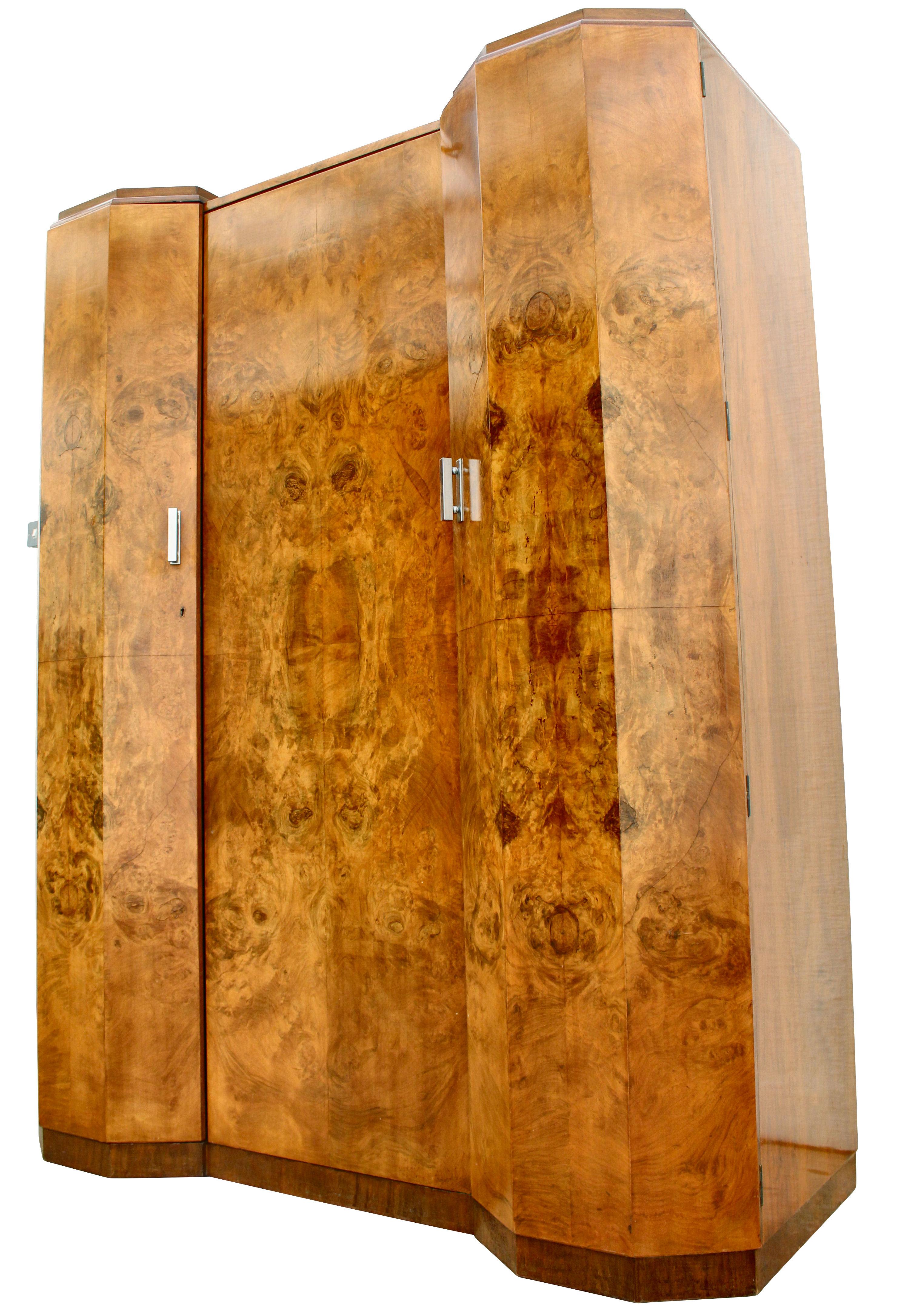 We hope the images offered go some way to demonstrate how truly wonderful this Art Deco gem is. For your consideration is this fabulously shaped triple wardrobe in heavily figured walnut veneer. This inverted breakfront has two hex shaped doors with