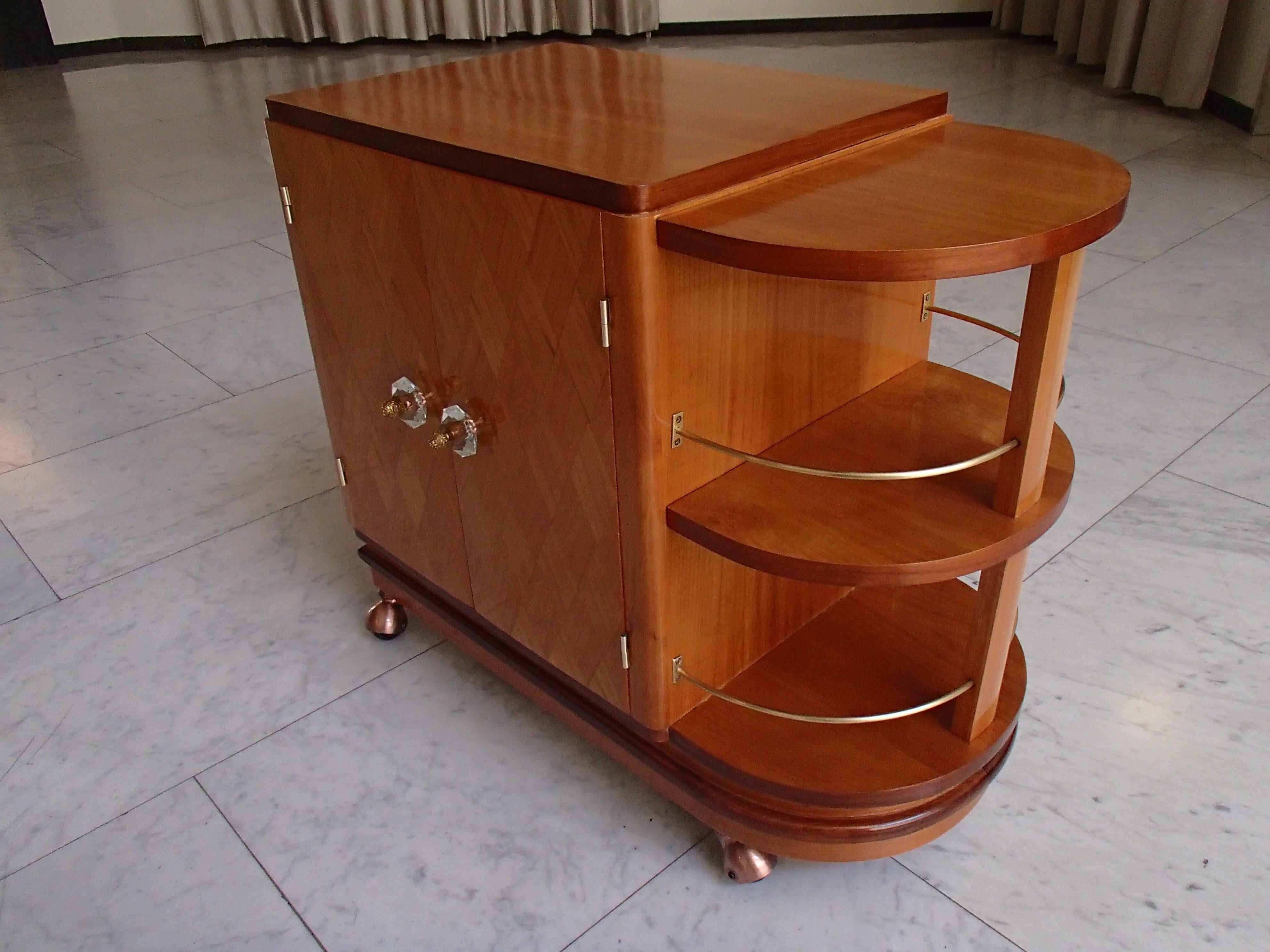 Art Deco trolley bar with 2 doors and bottle compartment on copper wheels.
Crystal and brass door handles and handle with plexiglass.