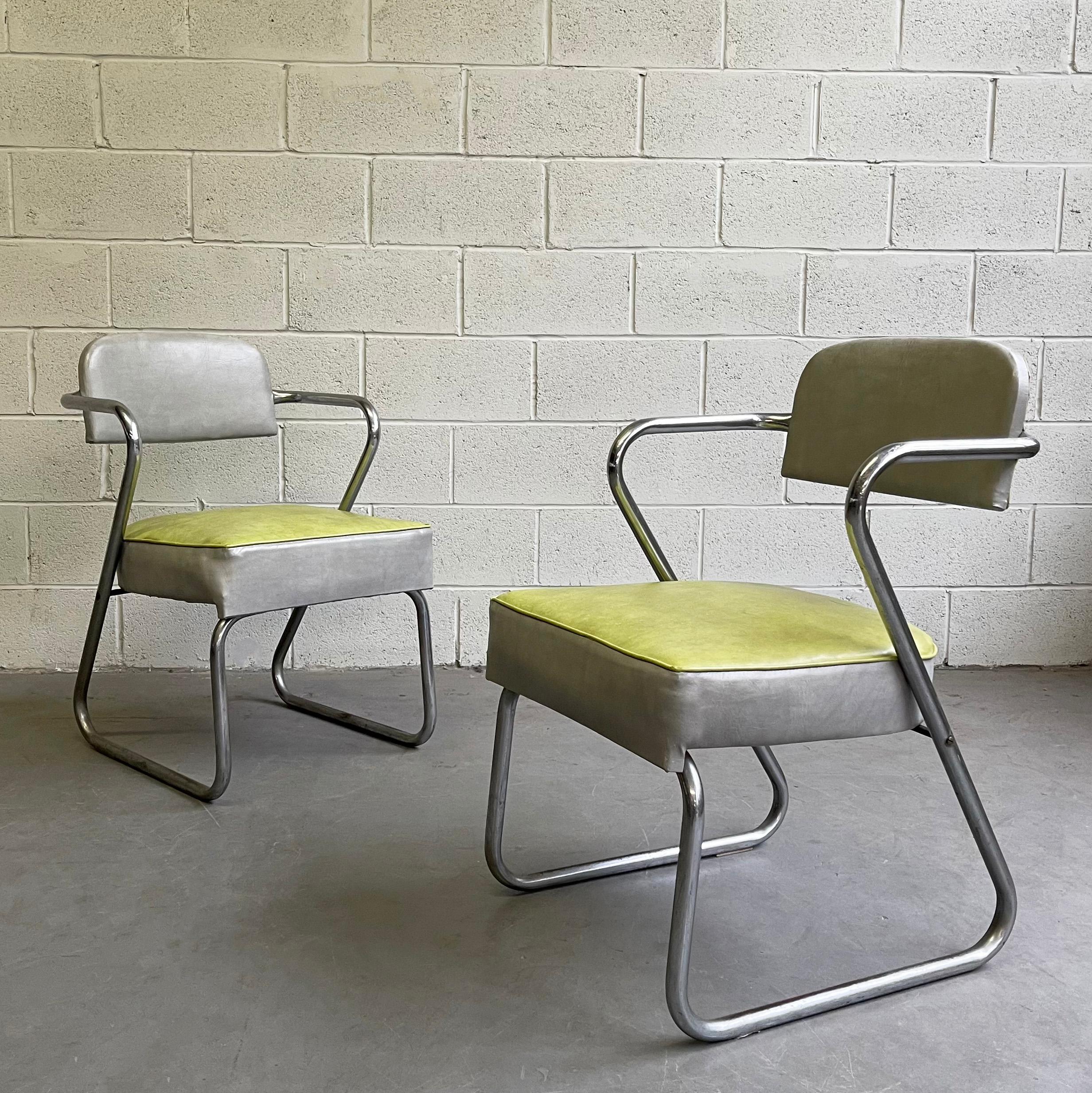 Pair of machine-age, Art Deco, armchairs by KEM Weber feature minimal, tubular chrome frames with two-tone, vinyl upholstery with nailhead detail.