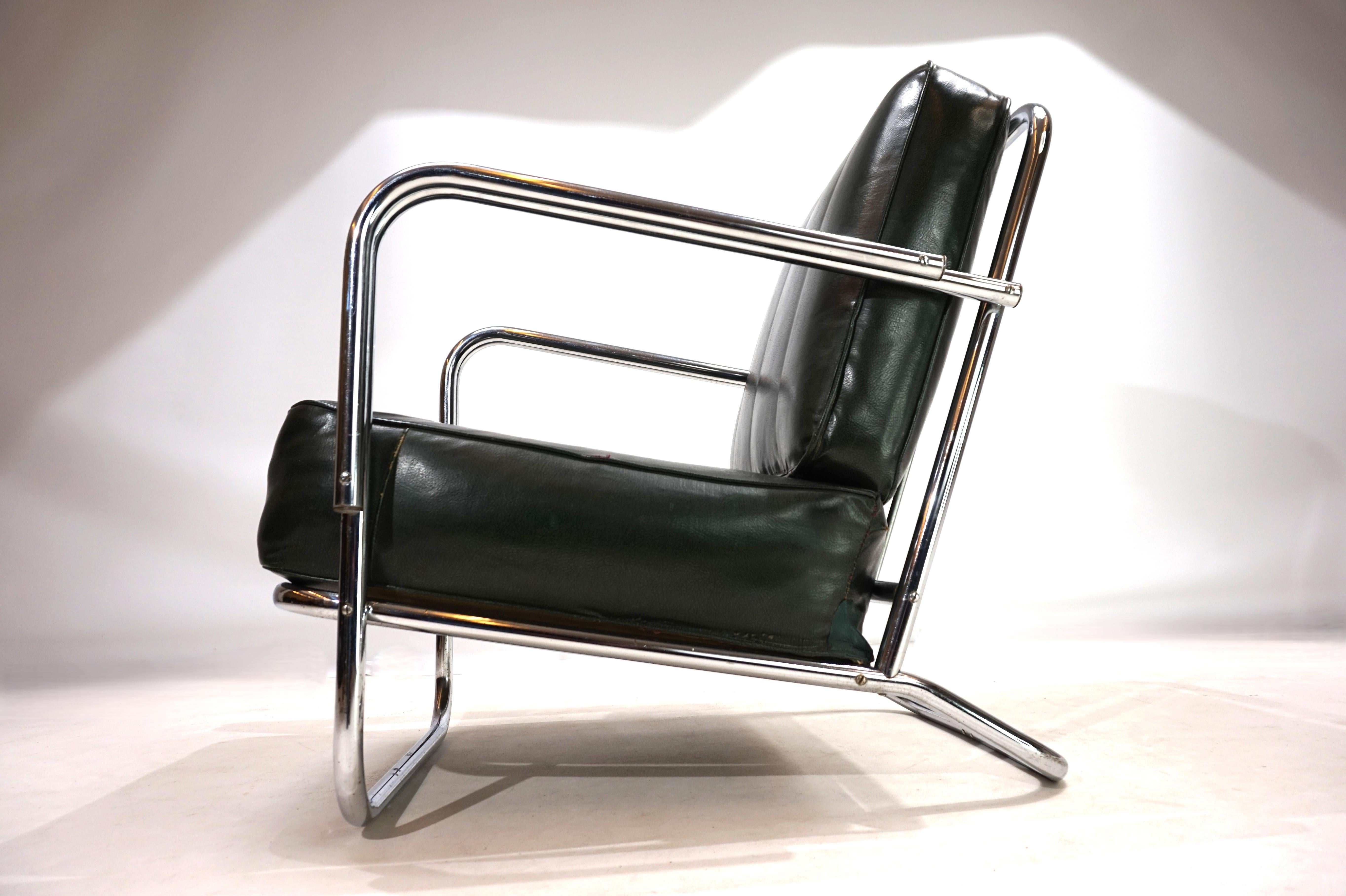 Una classica poltrona in tubolare d'acciaio in stile Art Déco degli anni '30. La poltrona è dotata di un rivestimento verde scuro in finta pelle e di una struttura in tubi cromati raddoppiati nella zona dei braccioli. Il cuscino del sedile presenta